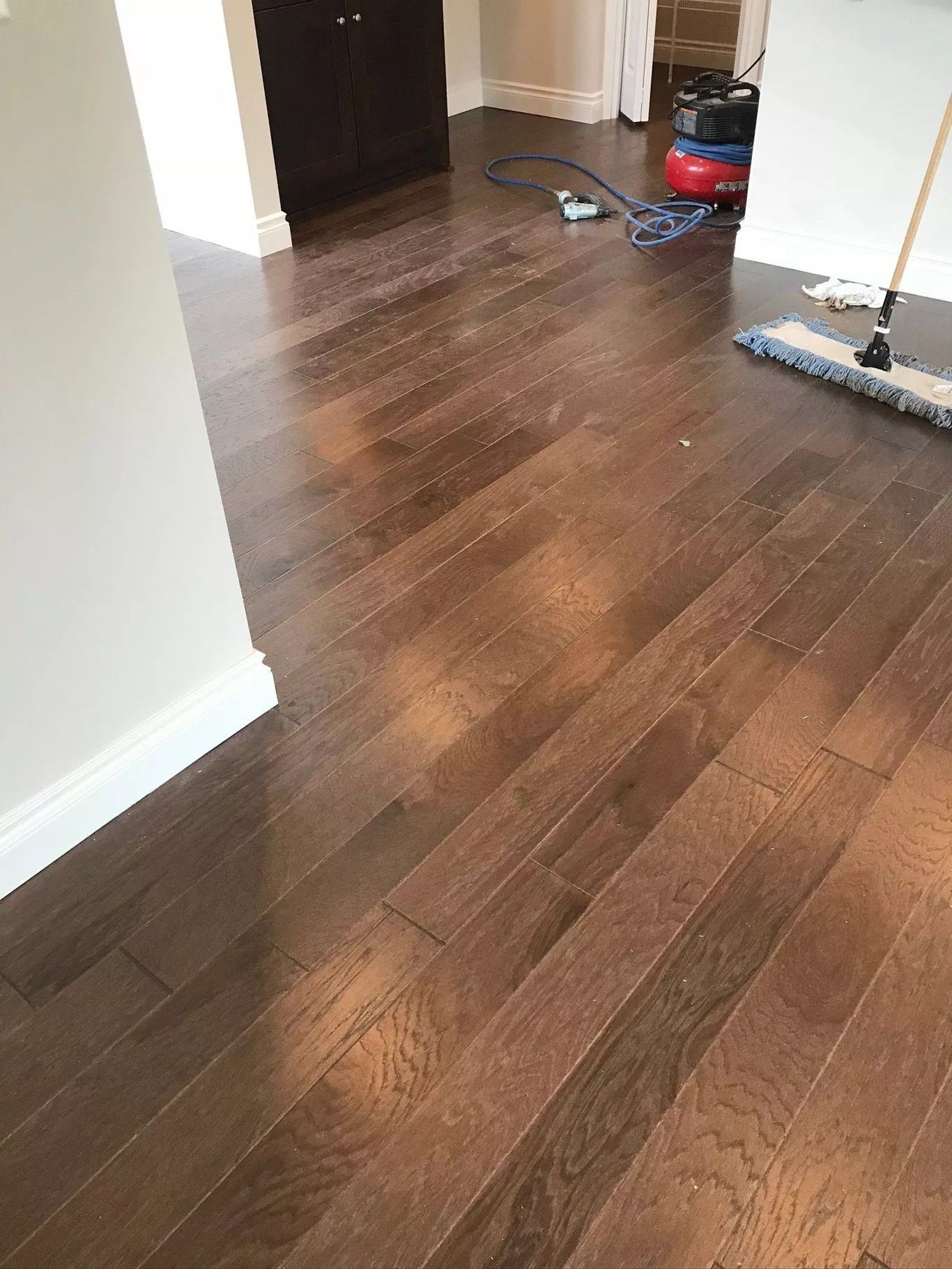A mop is sitting on a wooden floor next to a vacuum cleaner.