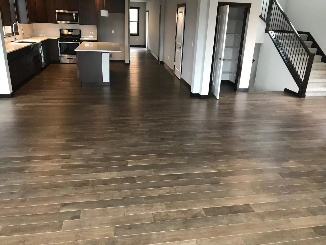 An empty kitchen with a wooden floor and stairs