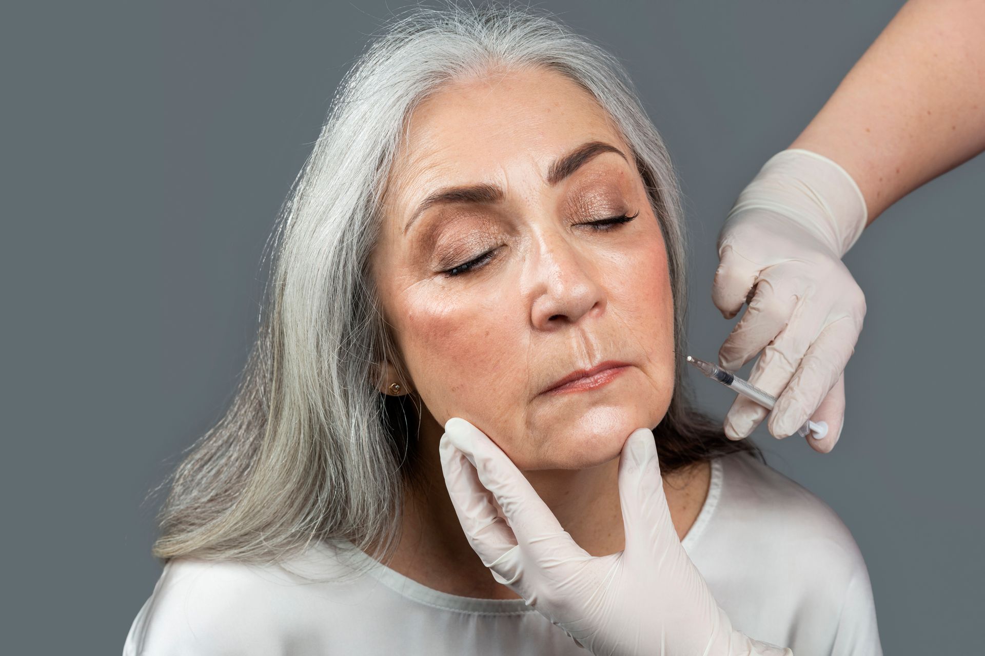 An older woman is getting a botox injection in her face.