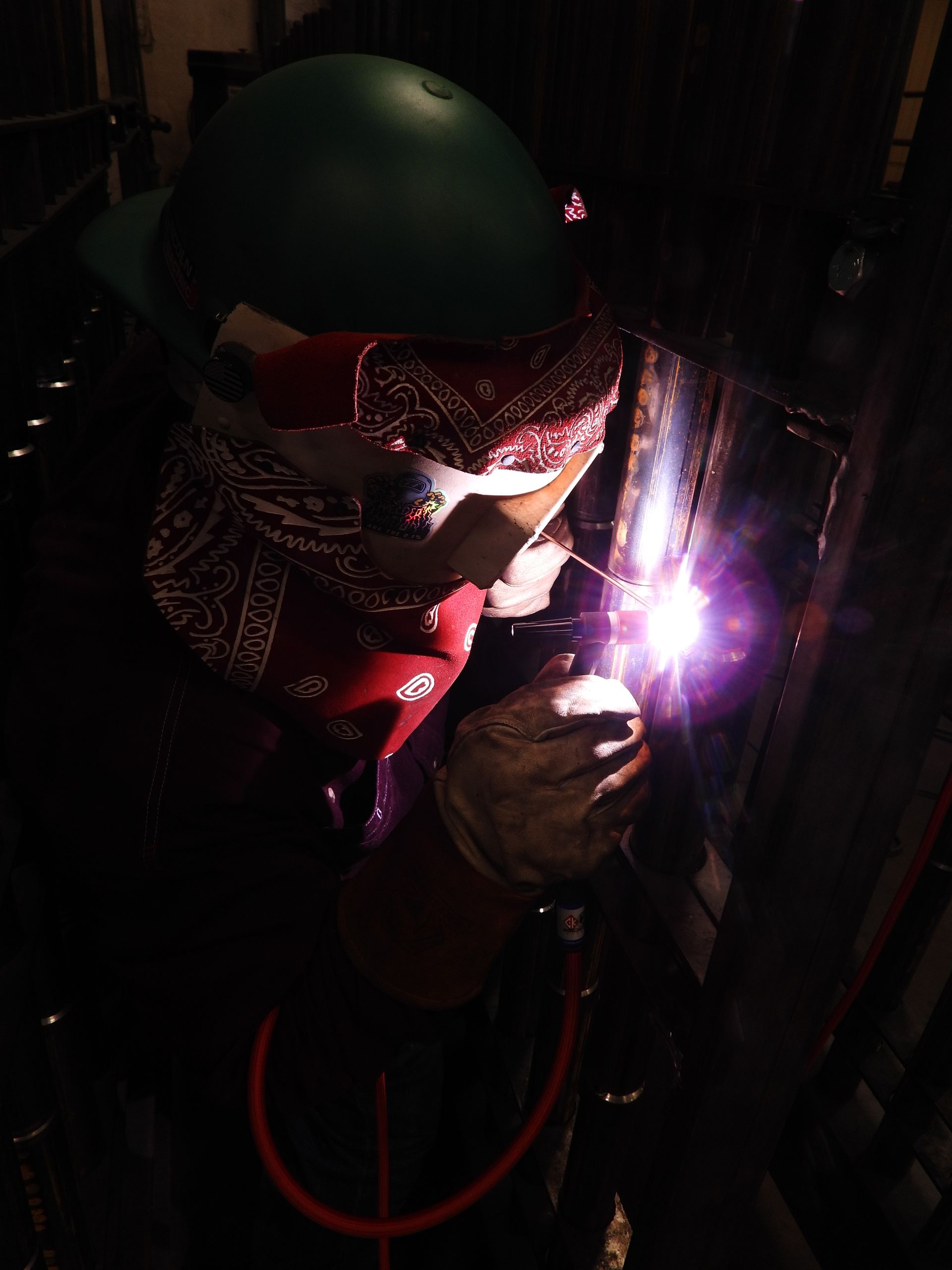 A man wearing a bandana is welding a piece of metal