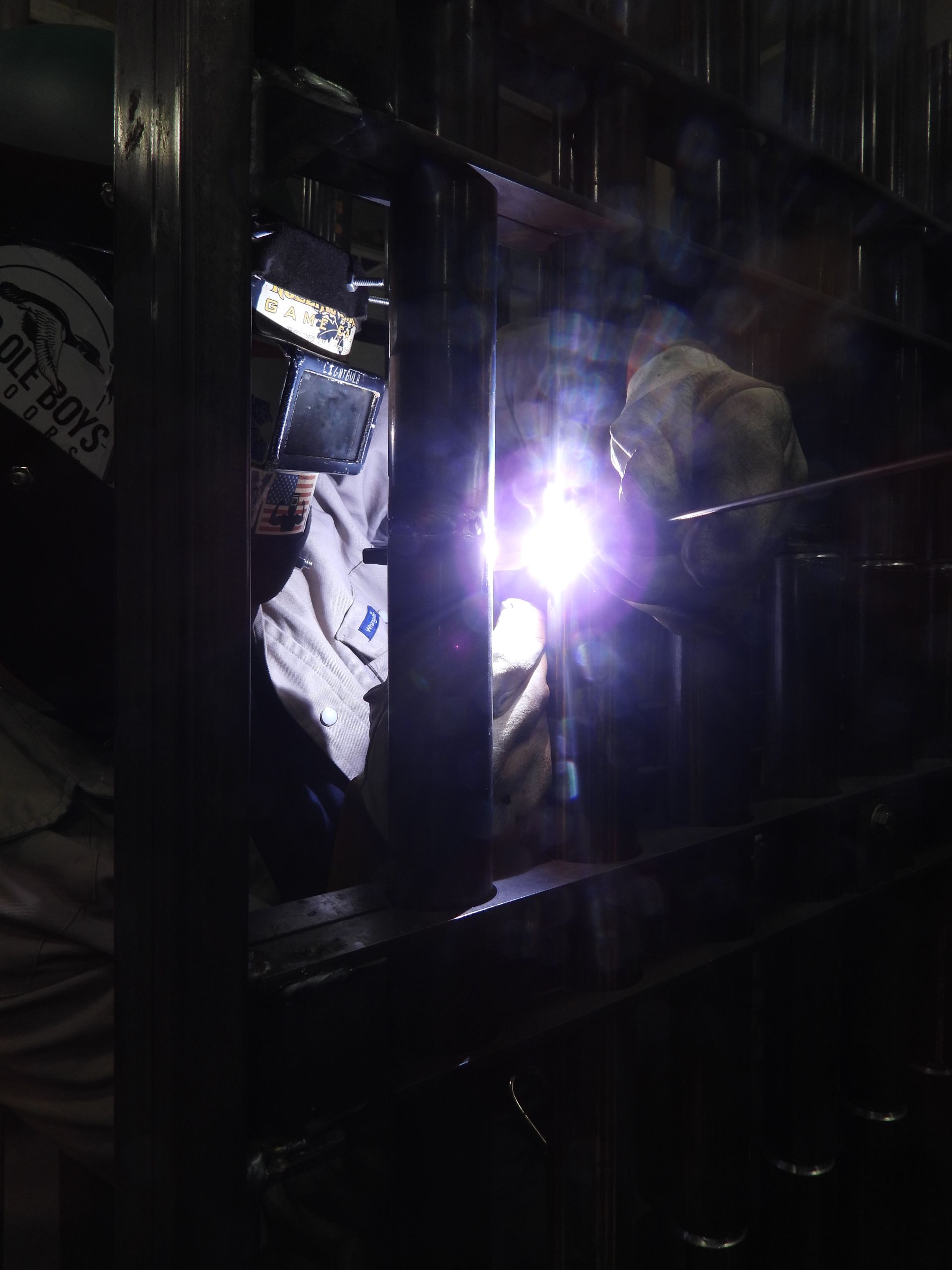 A man wearing a welding mask is welding a piece of metal