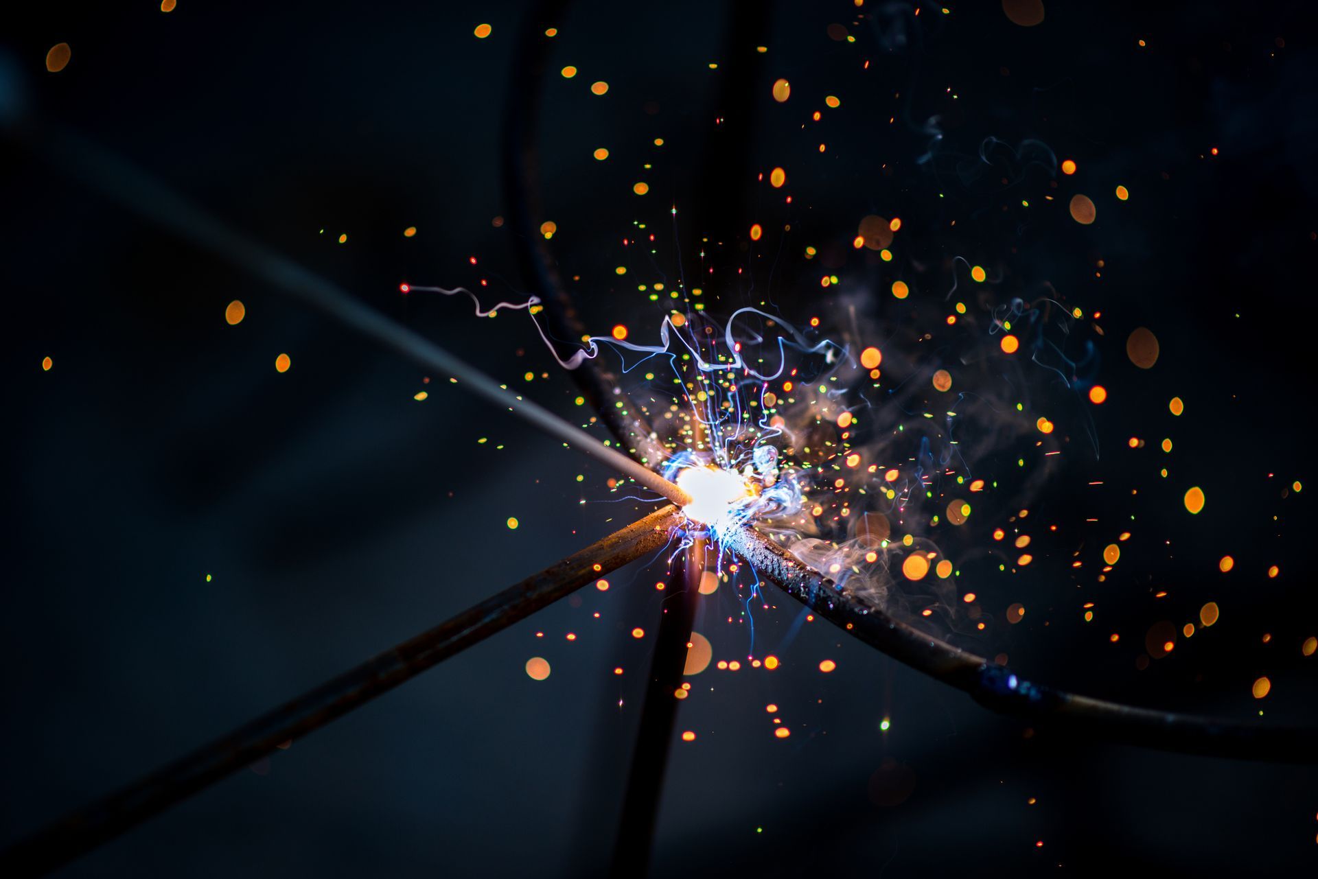 A close up of a person welding a piece of metal with sparks coming out of it.