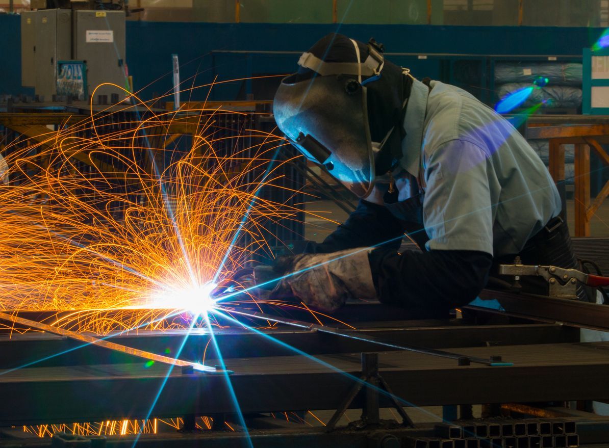 A man is welding a piece of metal in a factory.