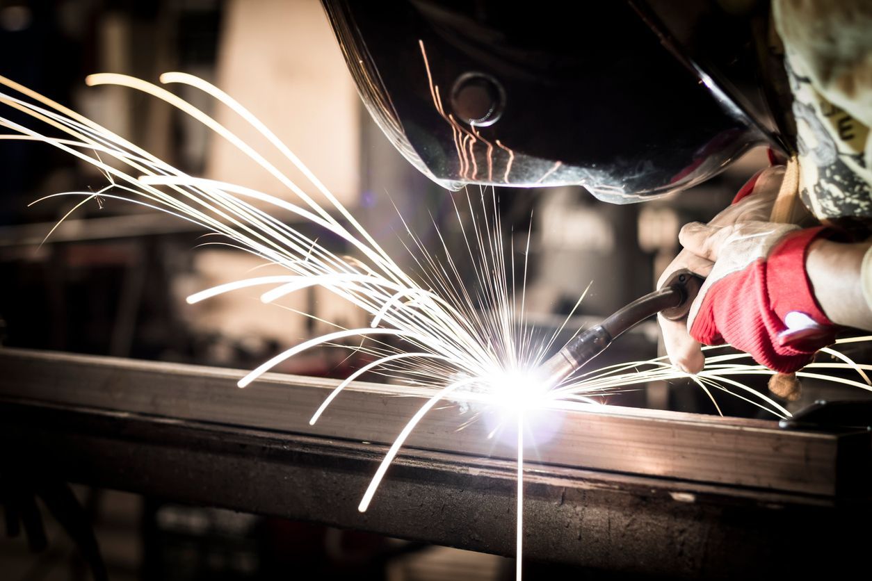 A man is welding a piece of metal in a factory.