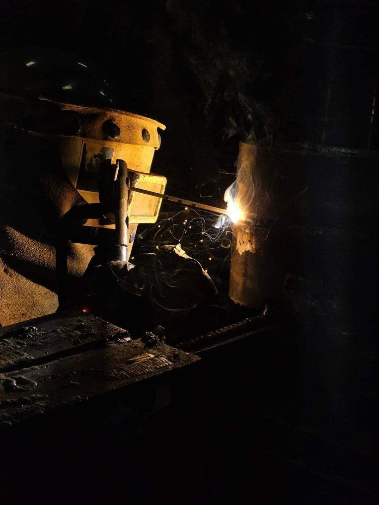 A person is welding a piece of metal in a dark room.