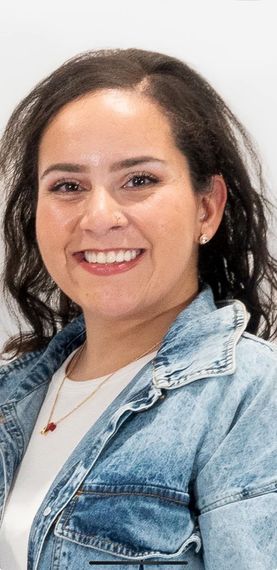 A close up of a woman wearing a denim jacket and smiling.