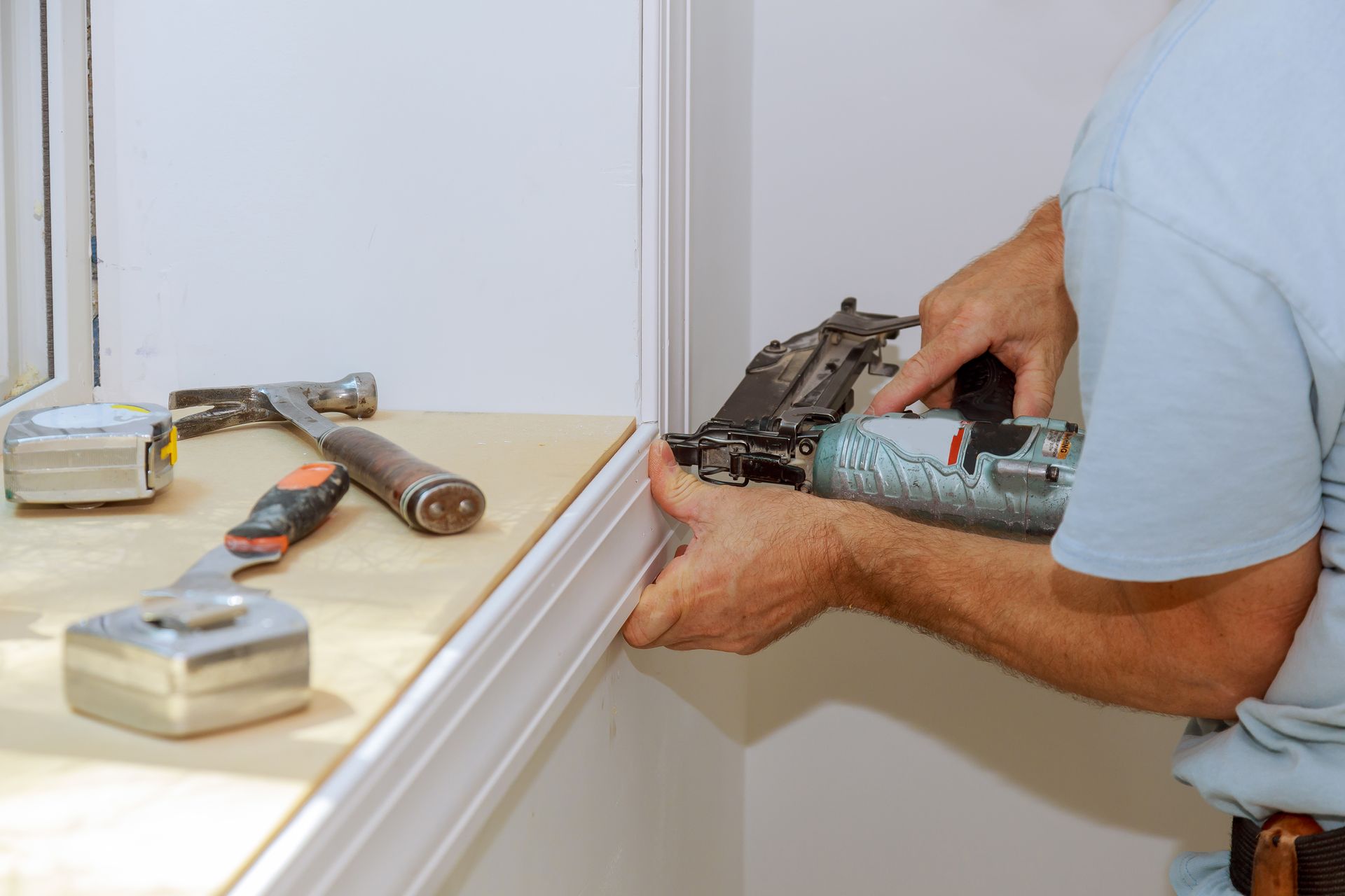 A handyman carefully installing trim around a window, ensuring precise placement and a polished finish.