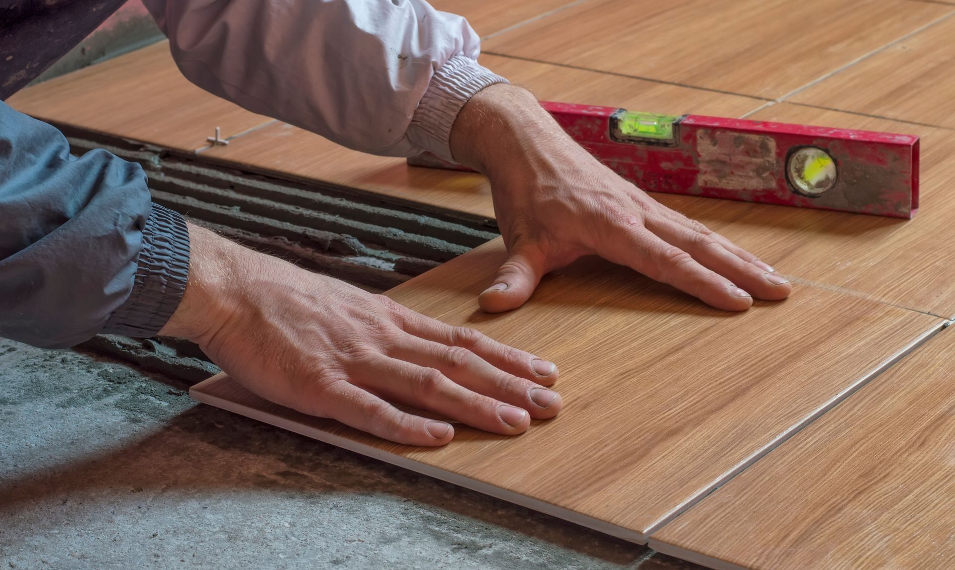 An experienced handyman skillfully repairing and installing tiles, carefully aligning and leveling each piece to create a seamless and attractive surface.