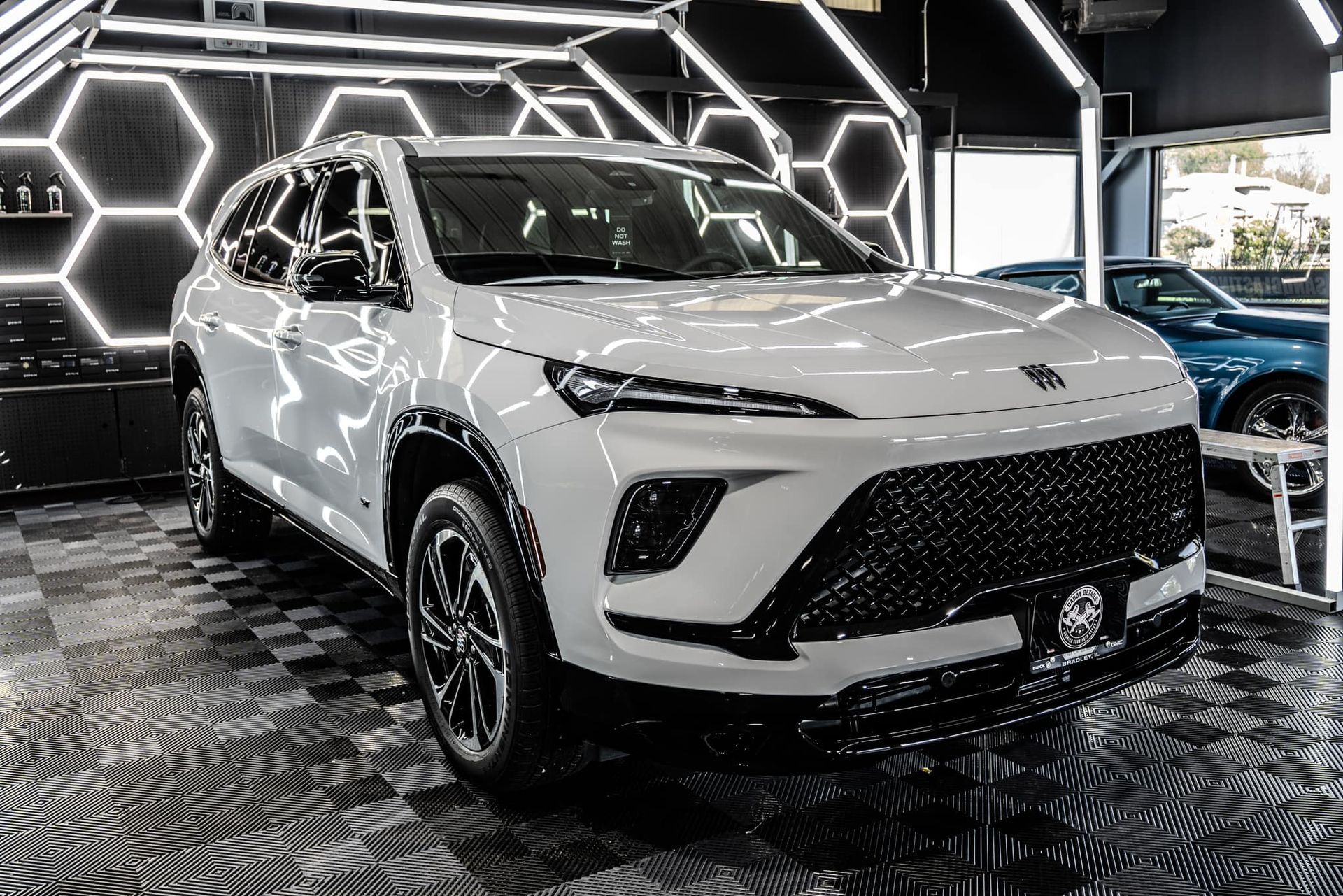 A white car with a black grill is parked in a garage.