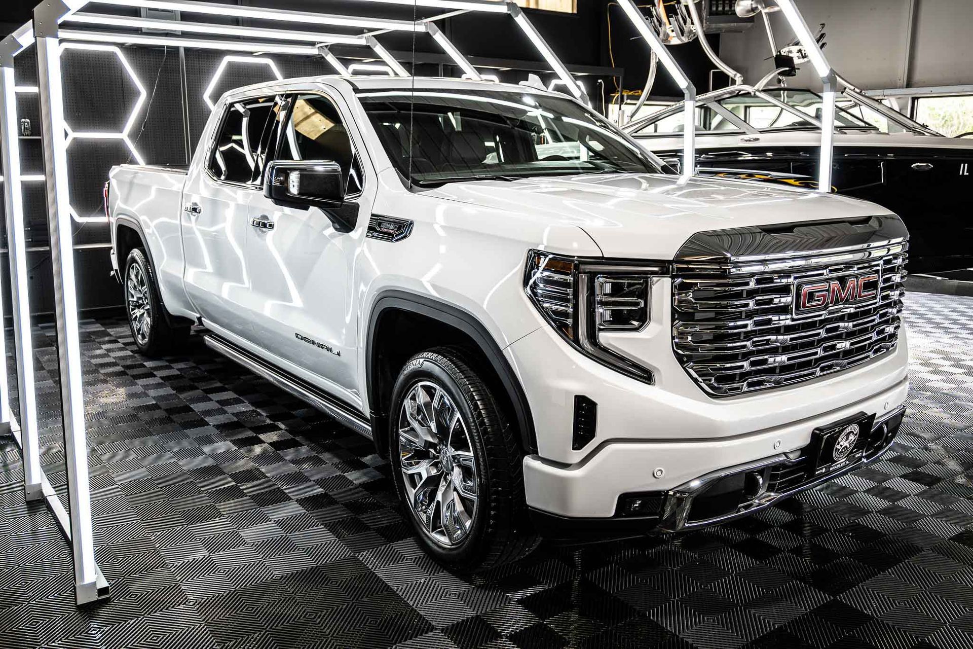 A white gmc sierra pickup truck is parked in a showroom.