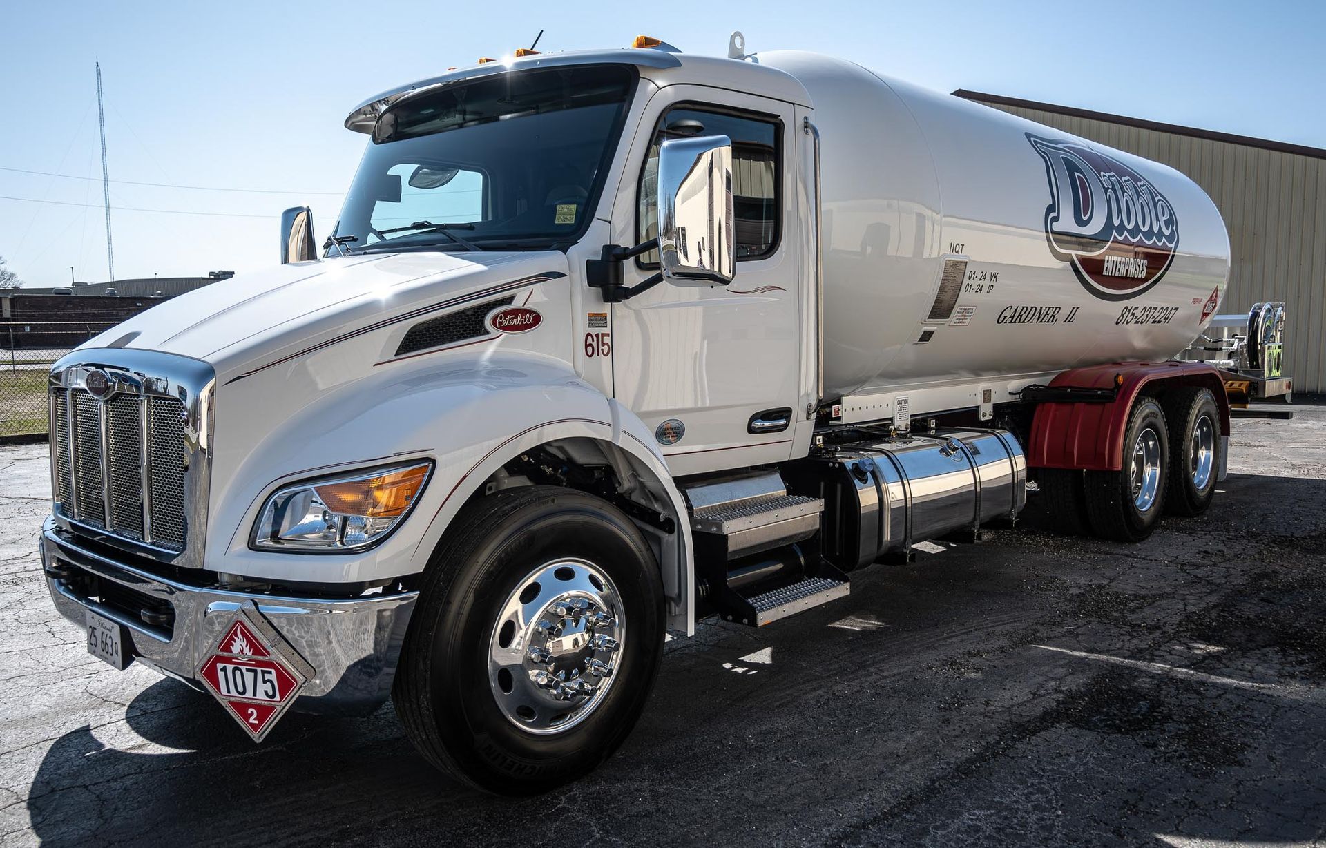 A white tanker truck is parked in front of a building.