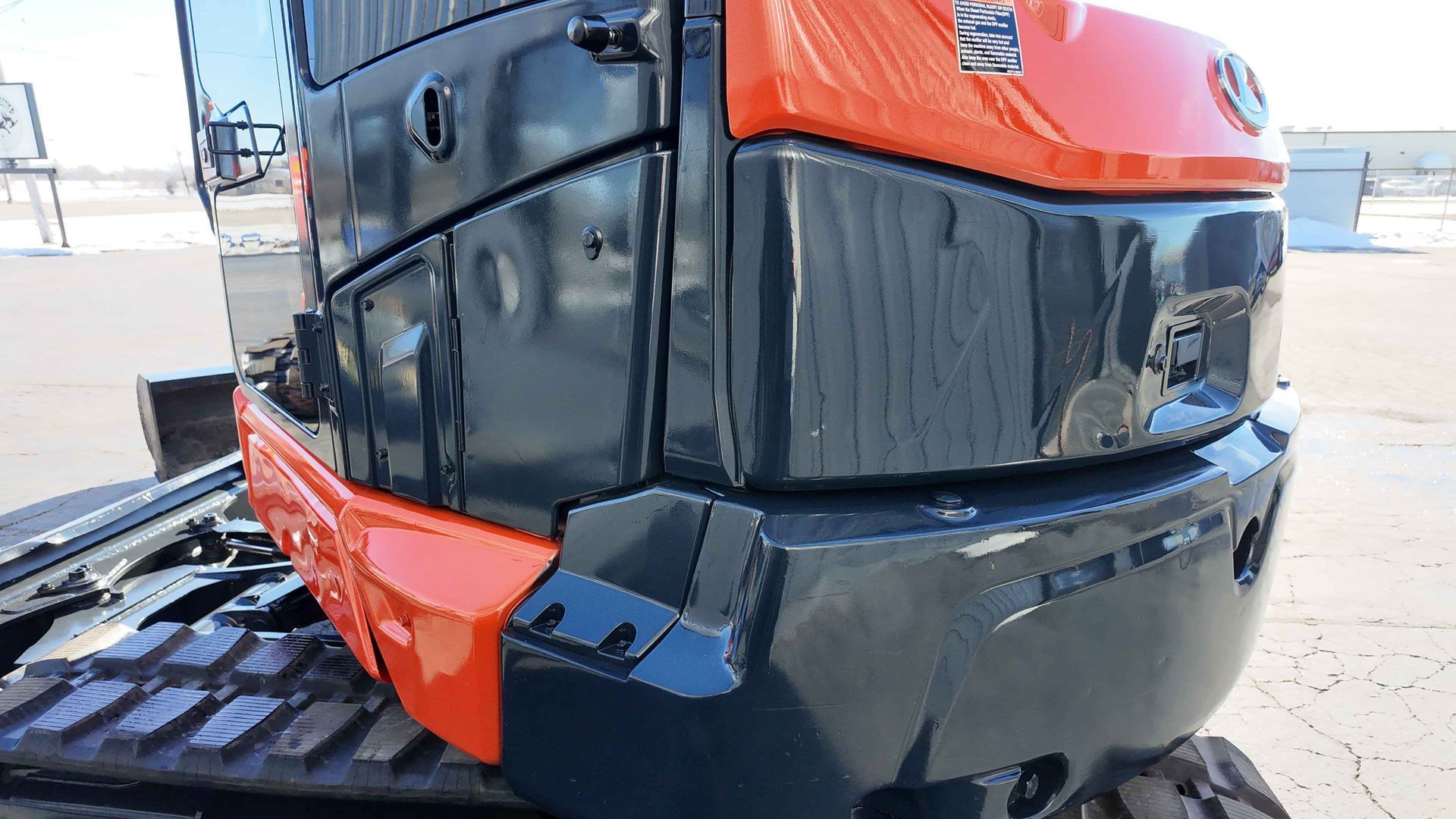 A red and black excavator is parked on a dirt road.