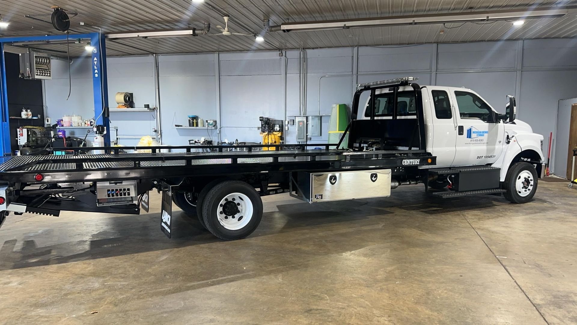 A white tow truck is parked in a garage.
