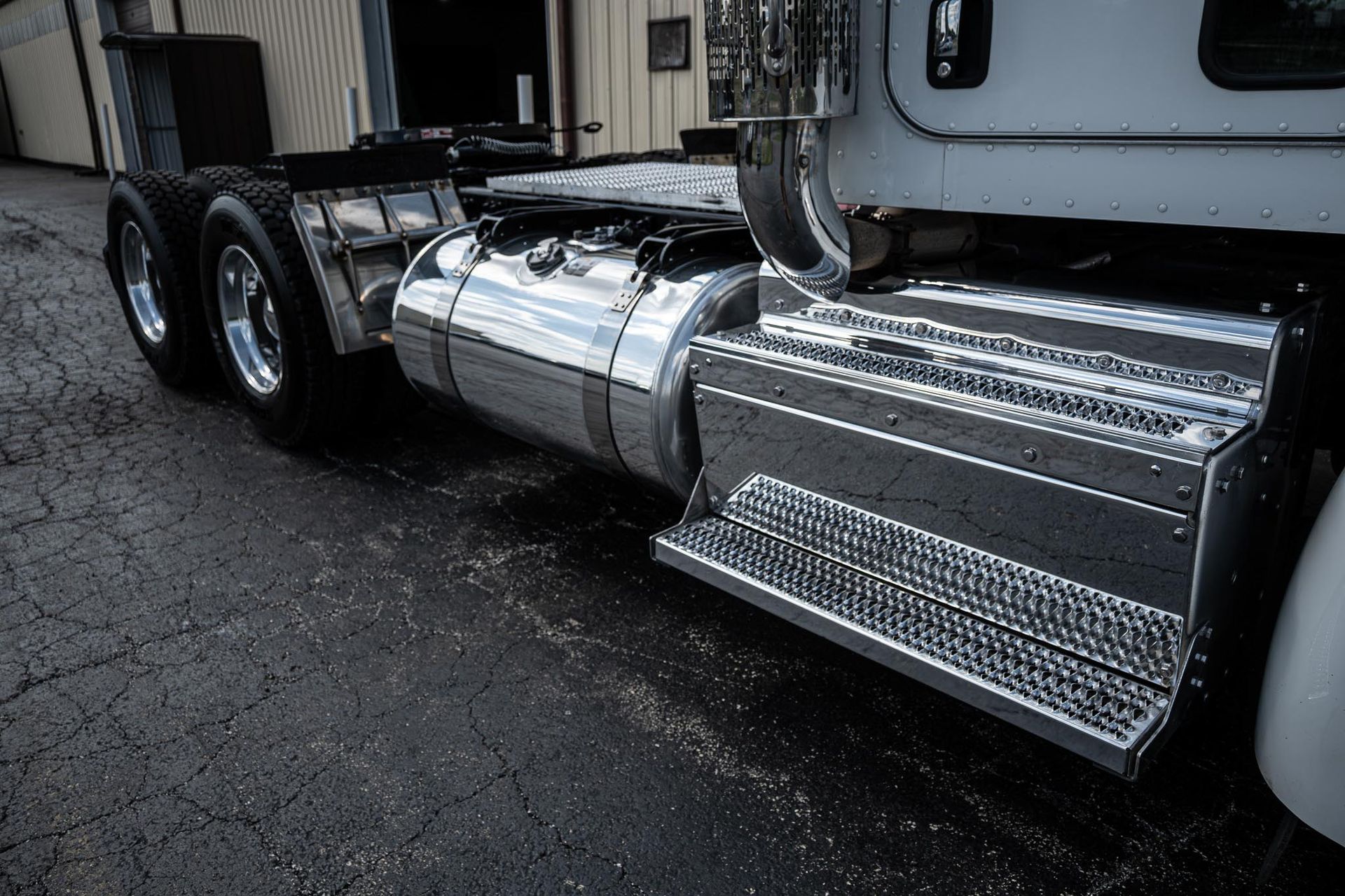 A silver semi truck is parked in front of a building after fleet detailing.
