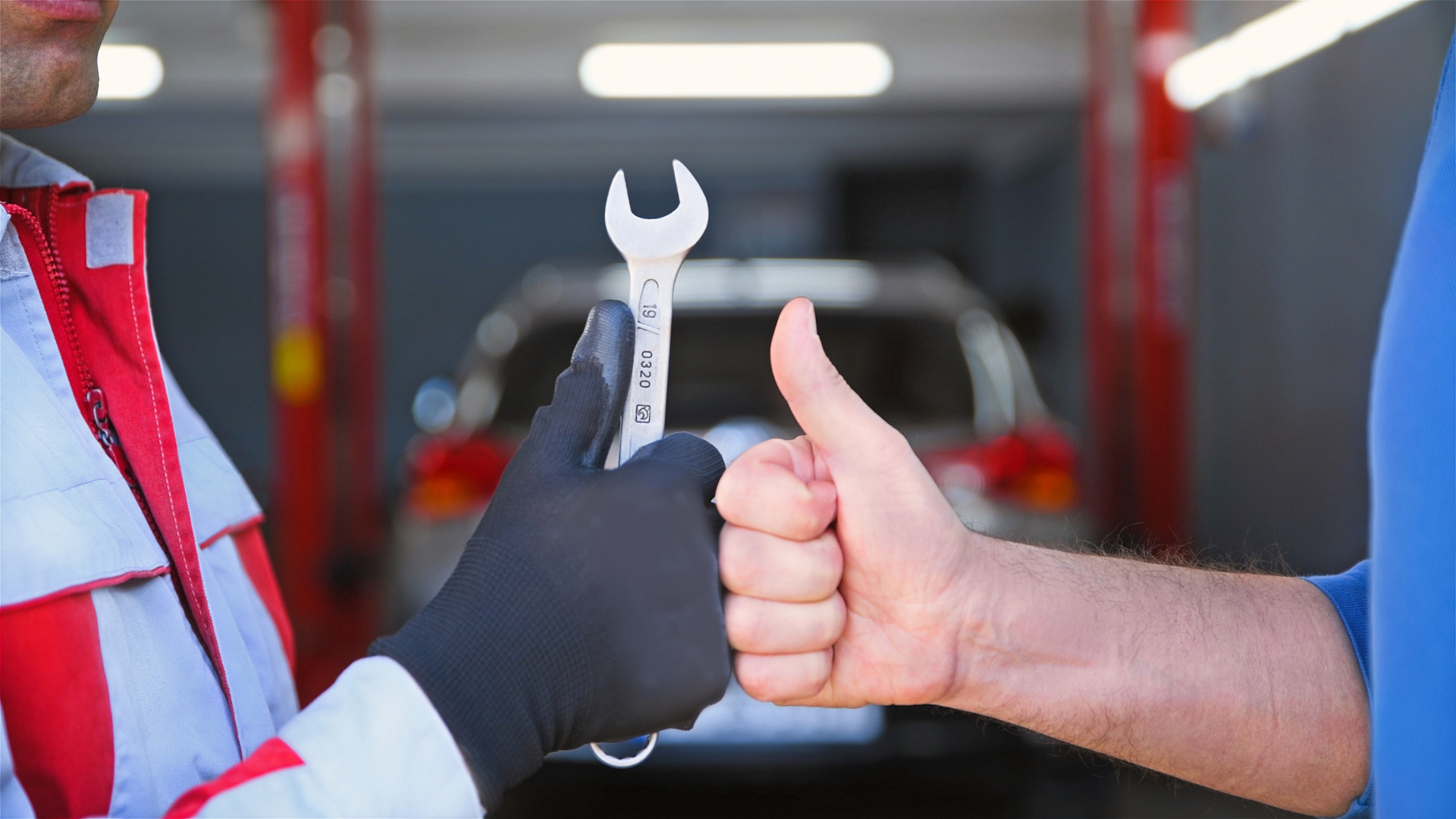 A man is looking under the hood of a car while holding a clipboard.