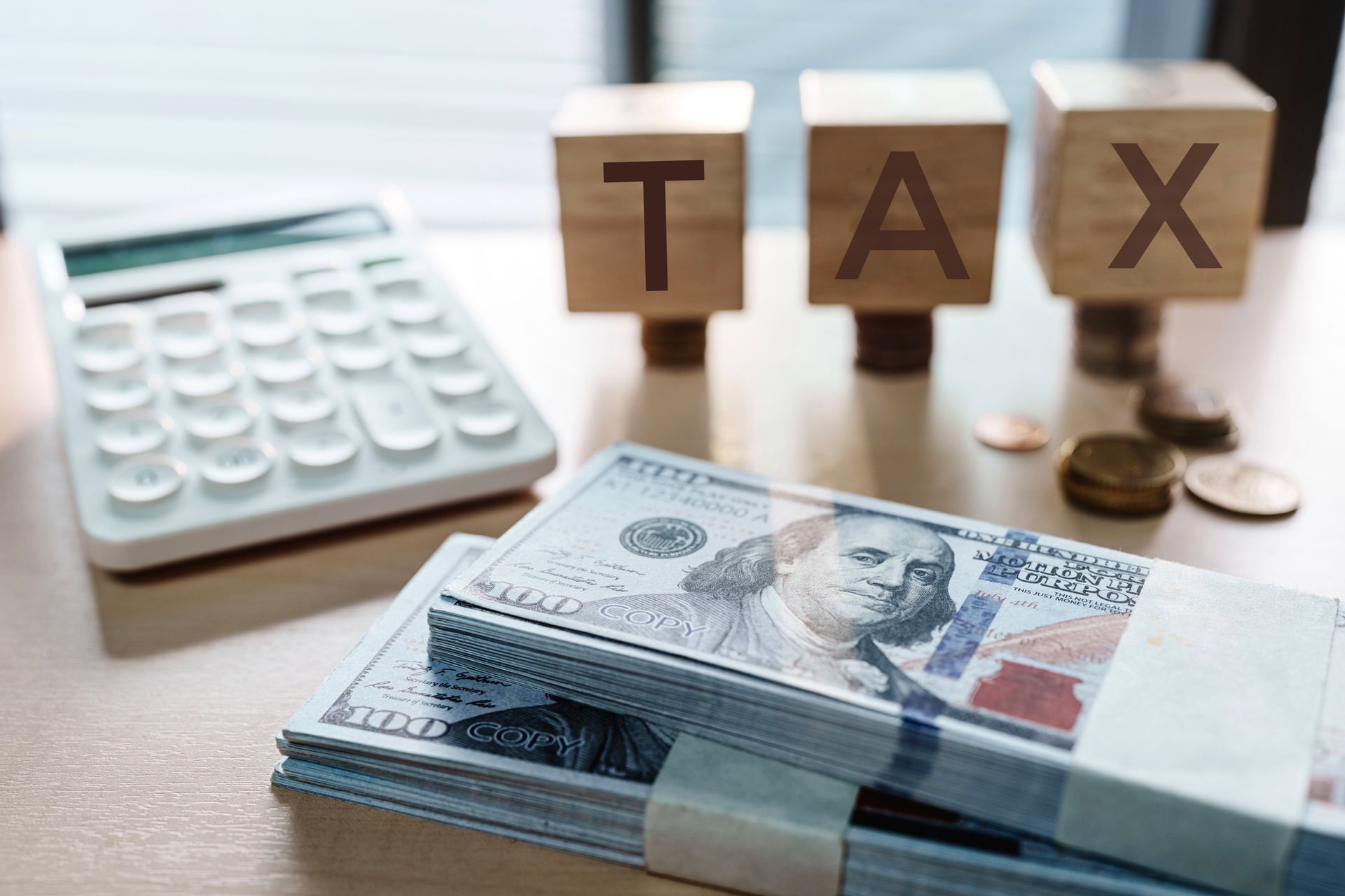 Tax sign with stacks of US bills and calculator.