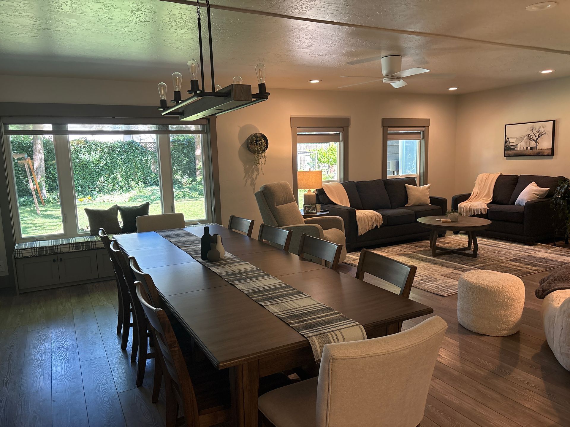 Single-story tan house exterior with large windows, stone patio, and air conditioner units