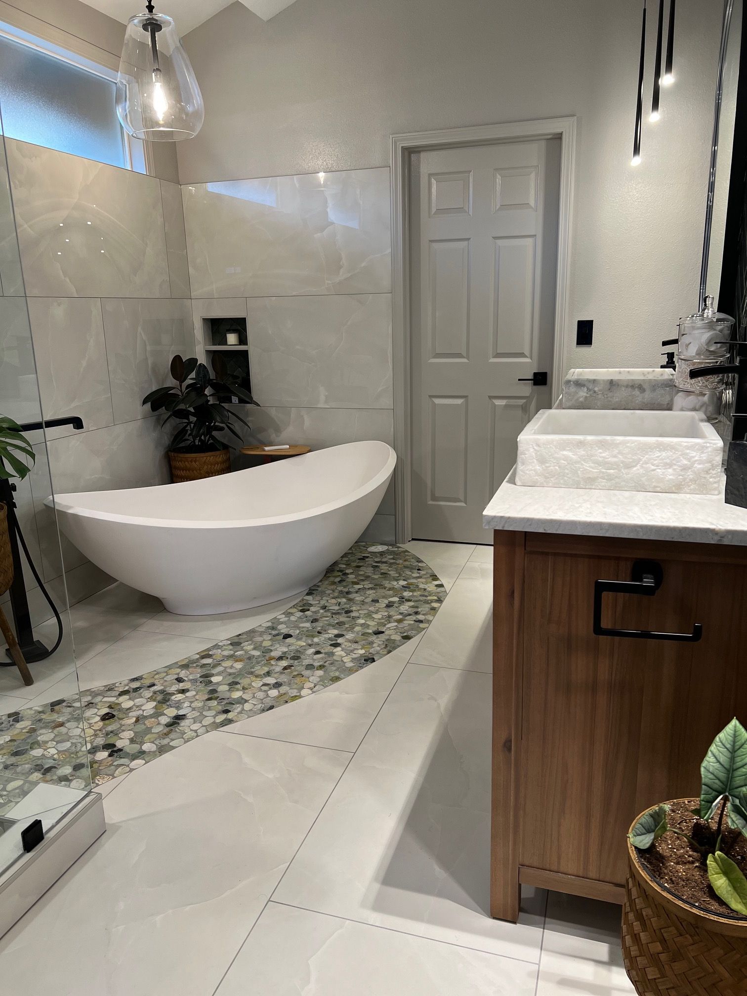 Modern bathroom with freestanding tub, marble vanity, tiled floor, and neutral decor