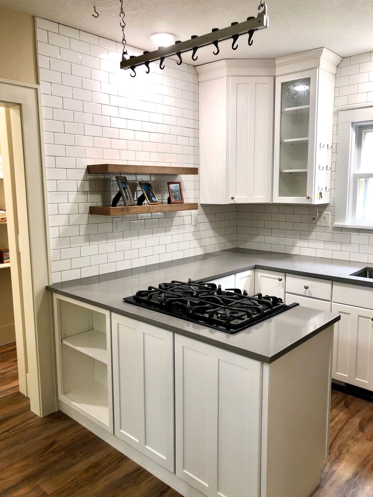 Modern kitchen with white cabinets, stainless steel fridge, black dishwasher, and hardwood floor