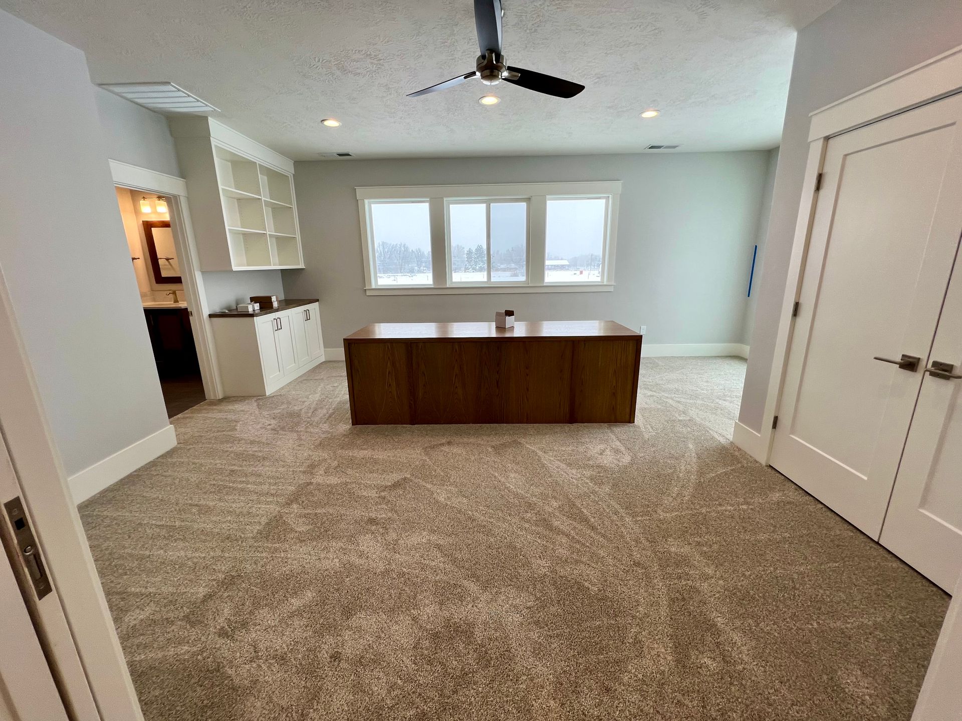 Modern open-plan living room and dining area with gray sofa, fireplace, wall-mounted TV, and ceiling fan.
