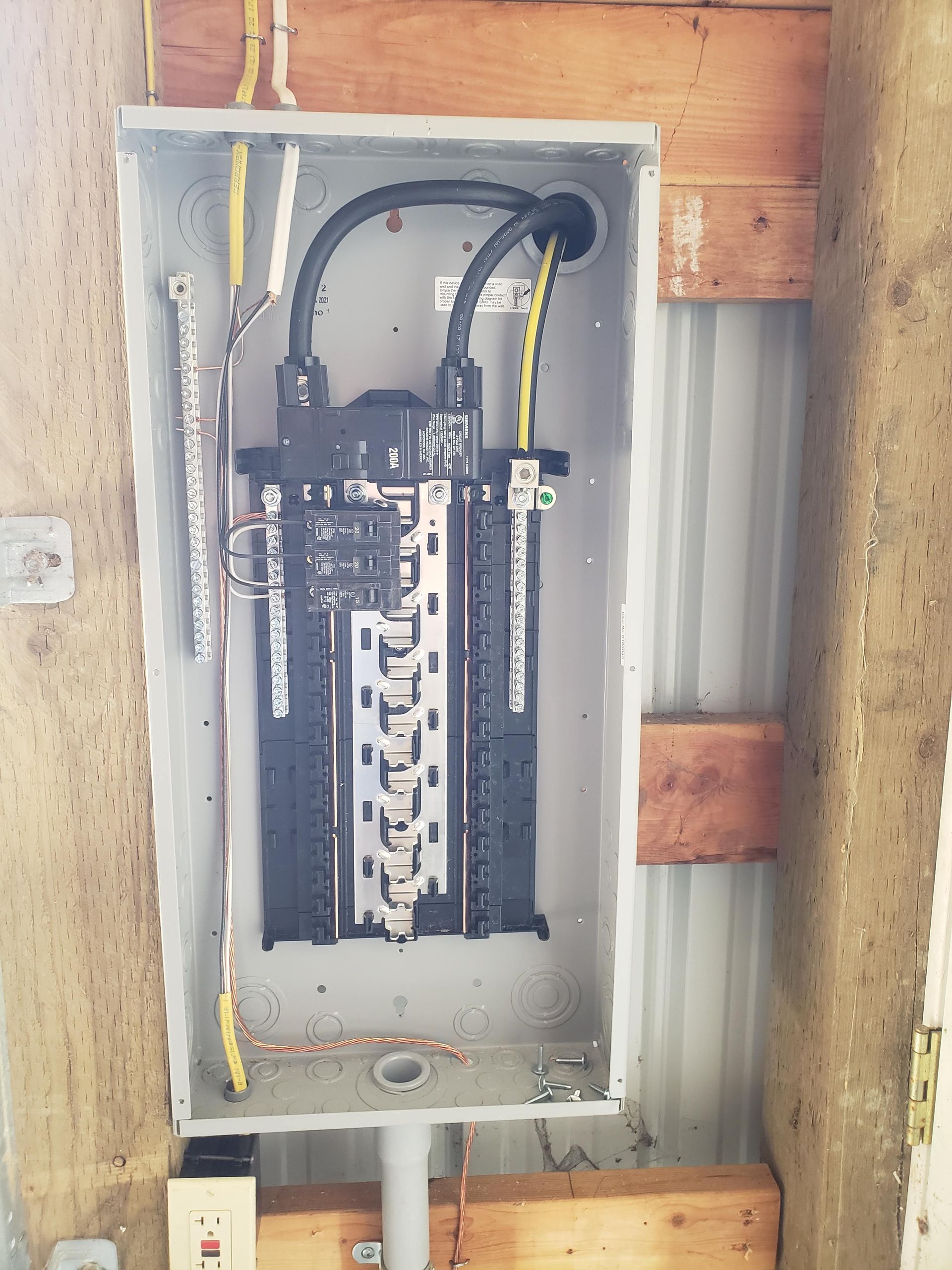 An electrical box is sitting on a wooden wall.