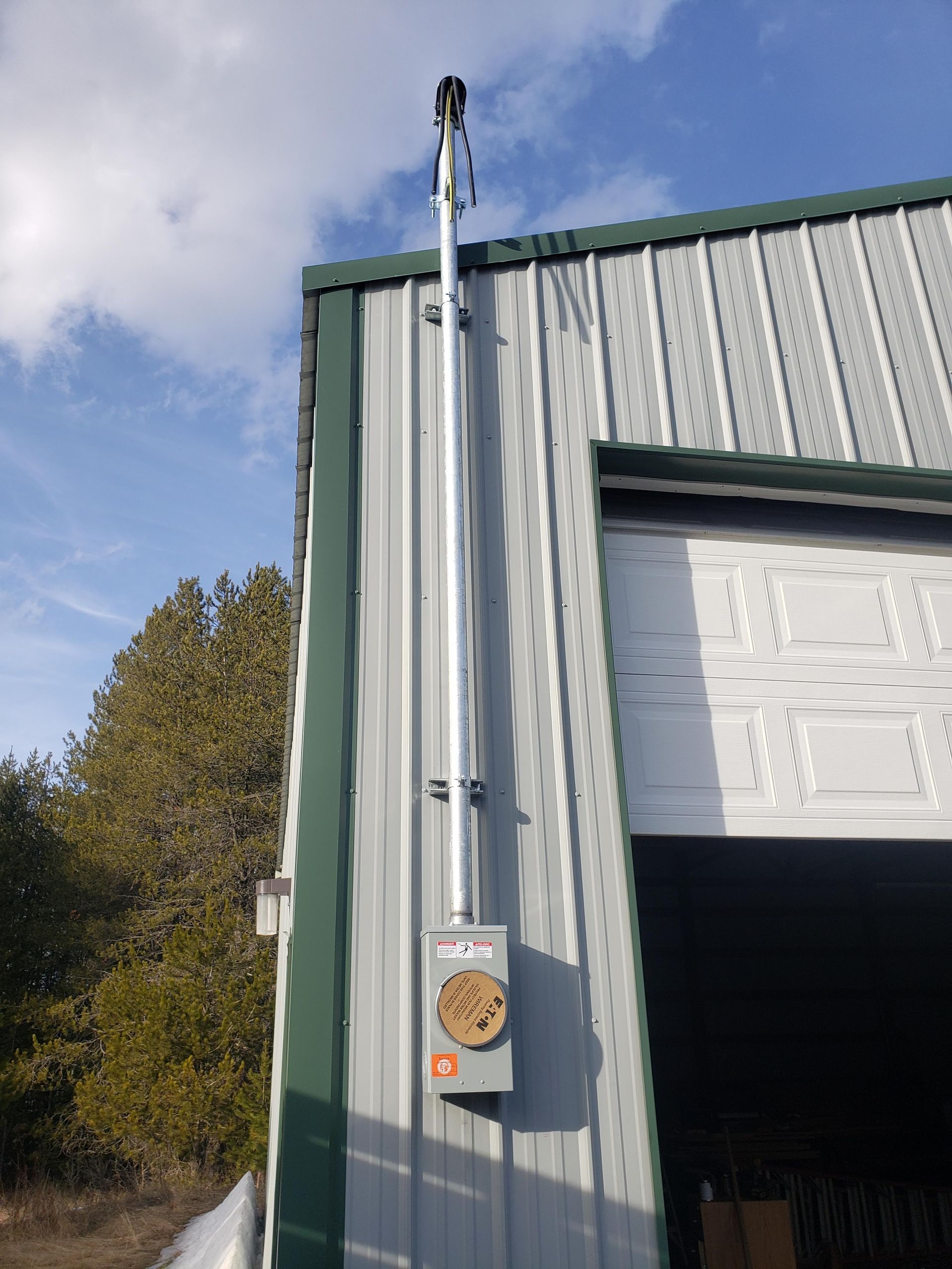 A metal building with a garage door and a box on the side of it.