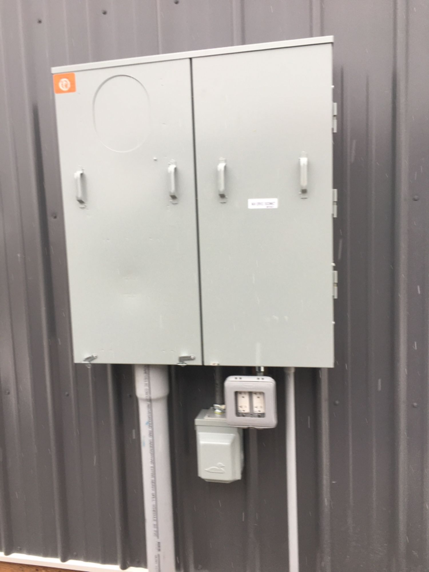 A large electrical box is attached to the side of a building.