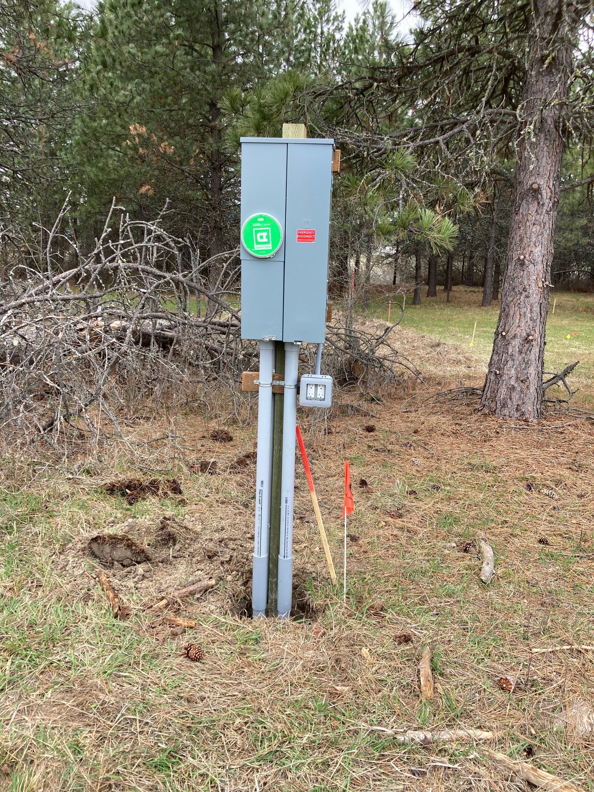 A large electrical box is sitting in the middle of a field.