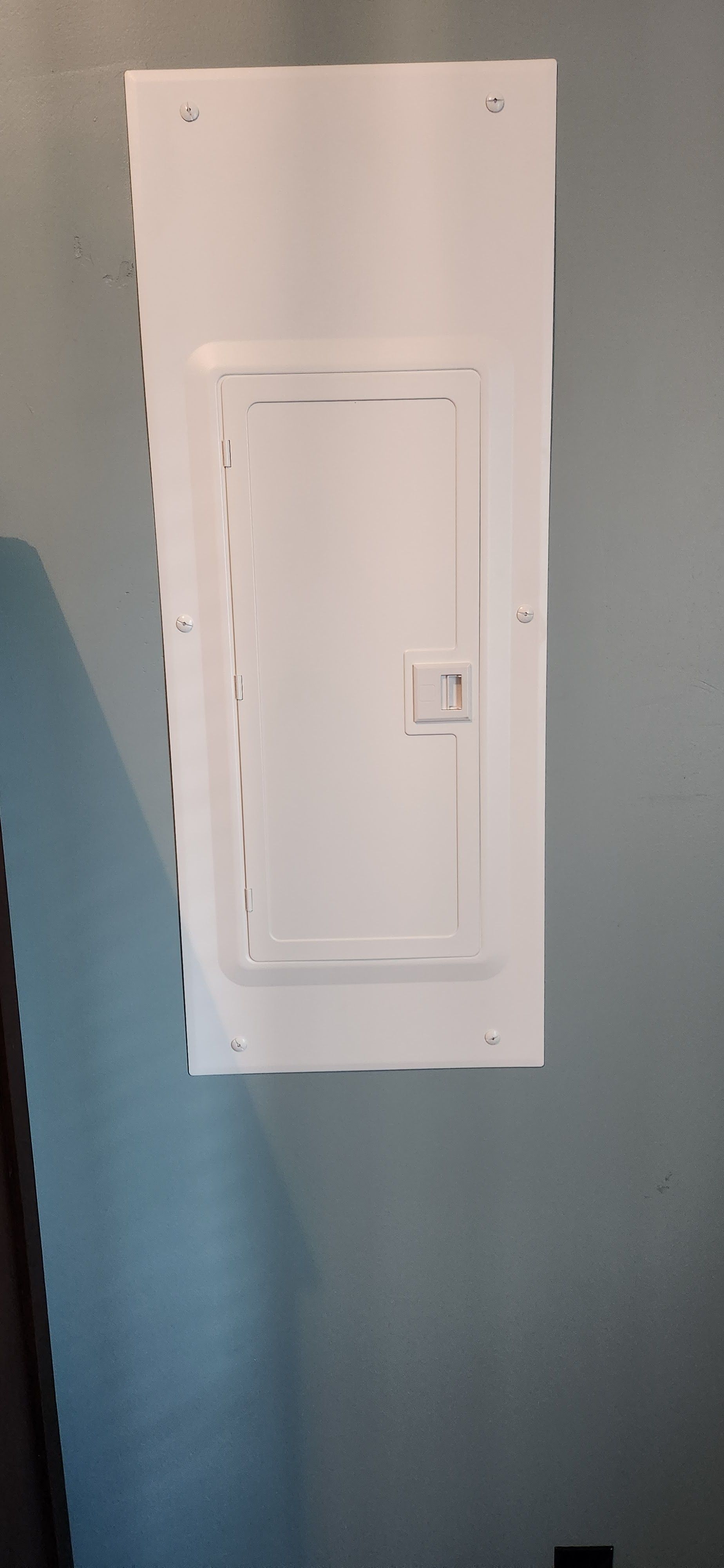 A white electrical box is hanging on a wall in a room.