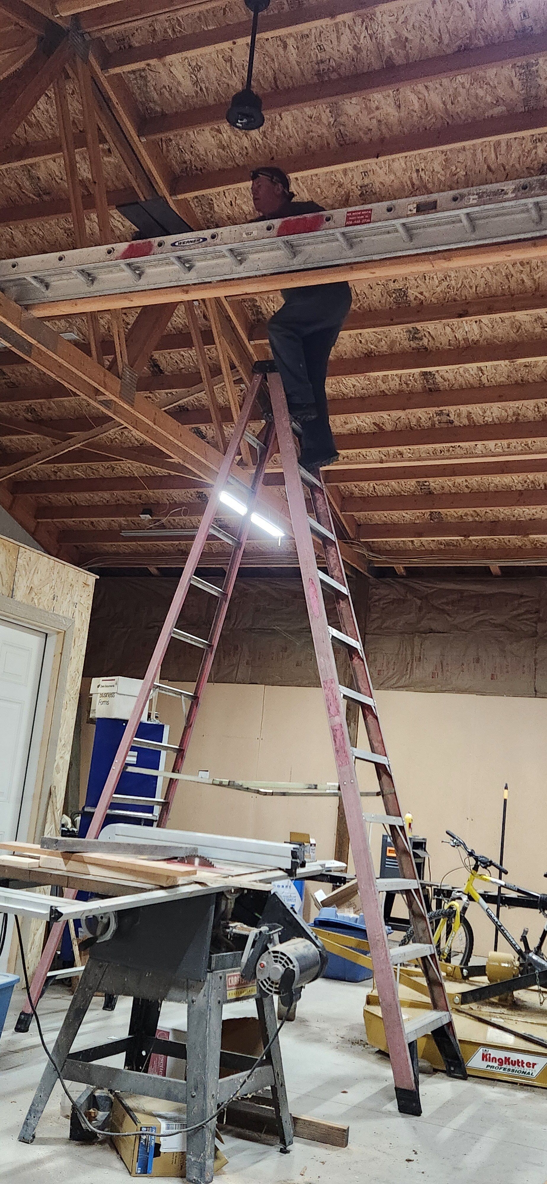 A man is standing on a ladder in a room.