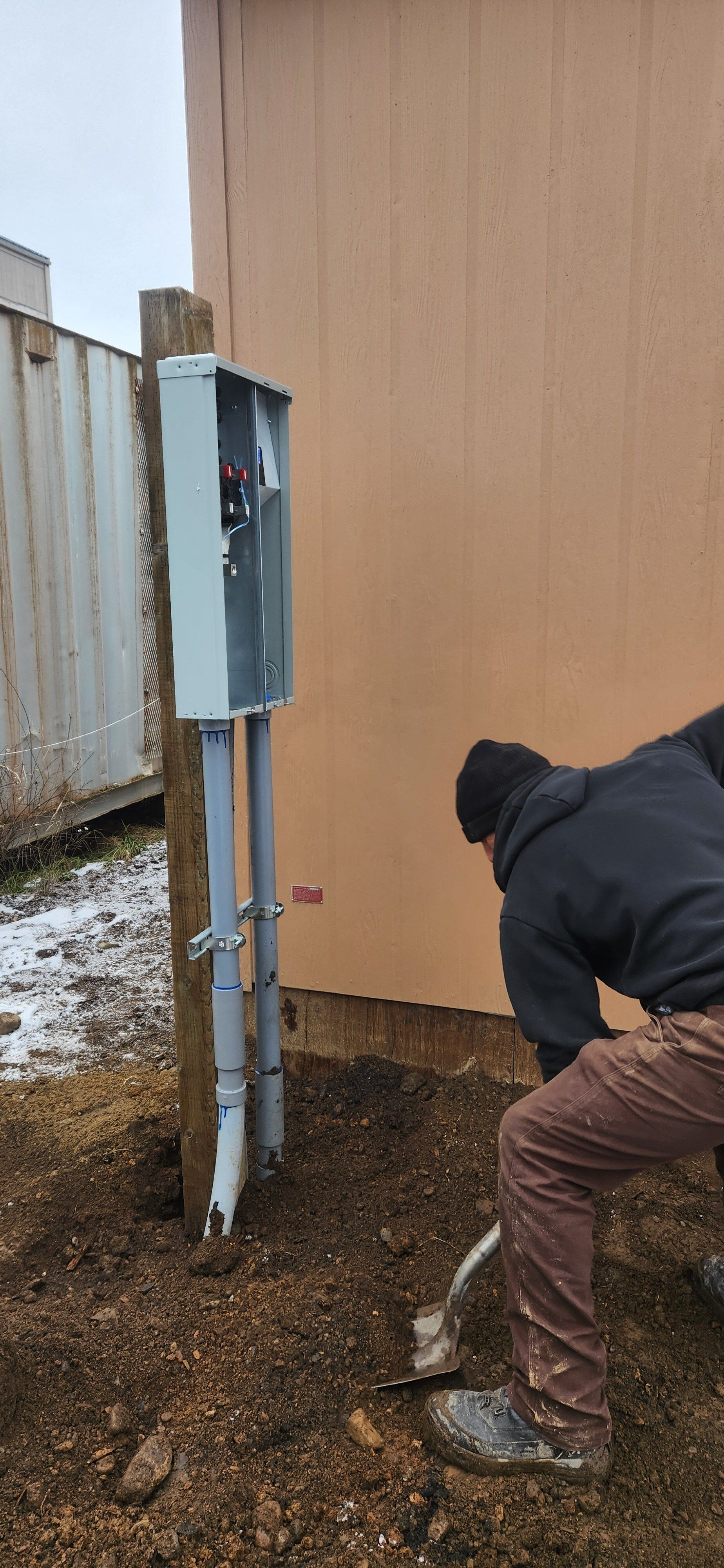 An electrician is working on a wall with a screwdriver.