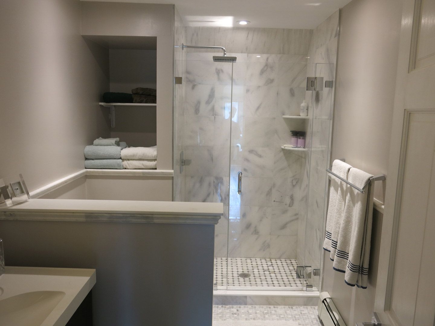 A bathroom with a walk in shower and a sink