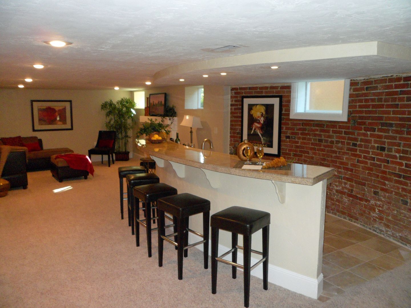 A basement with a bar and stools and a brick wall