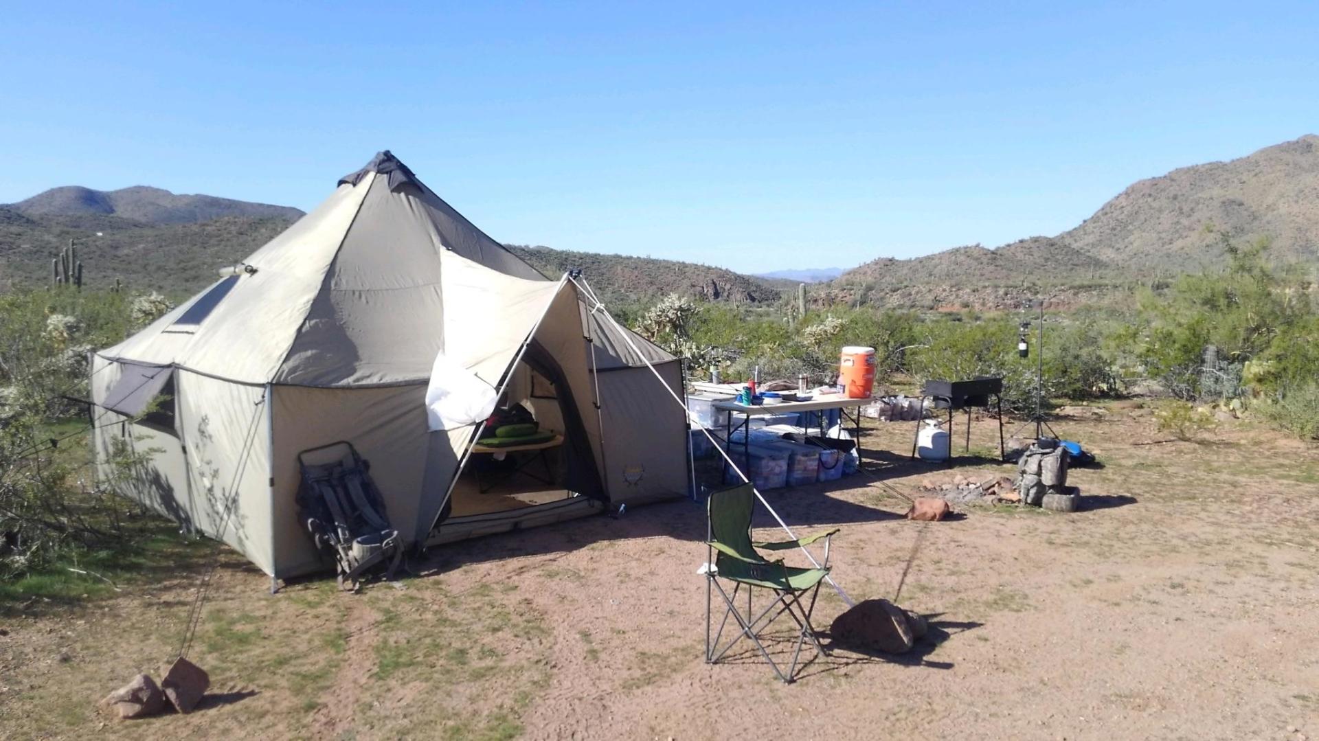 A large tent sits in the middle of a dirt field