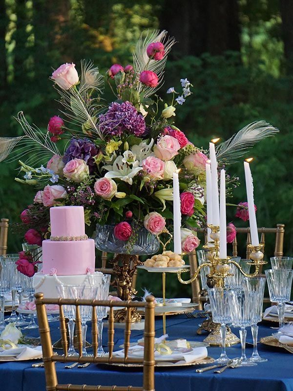 A table with a pink cake , candles , and flowers on it.