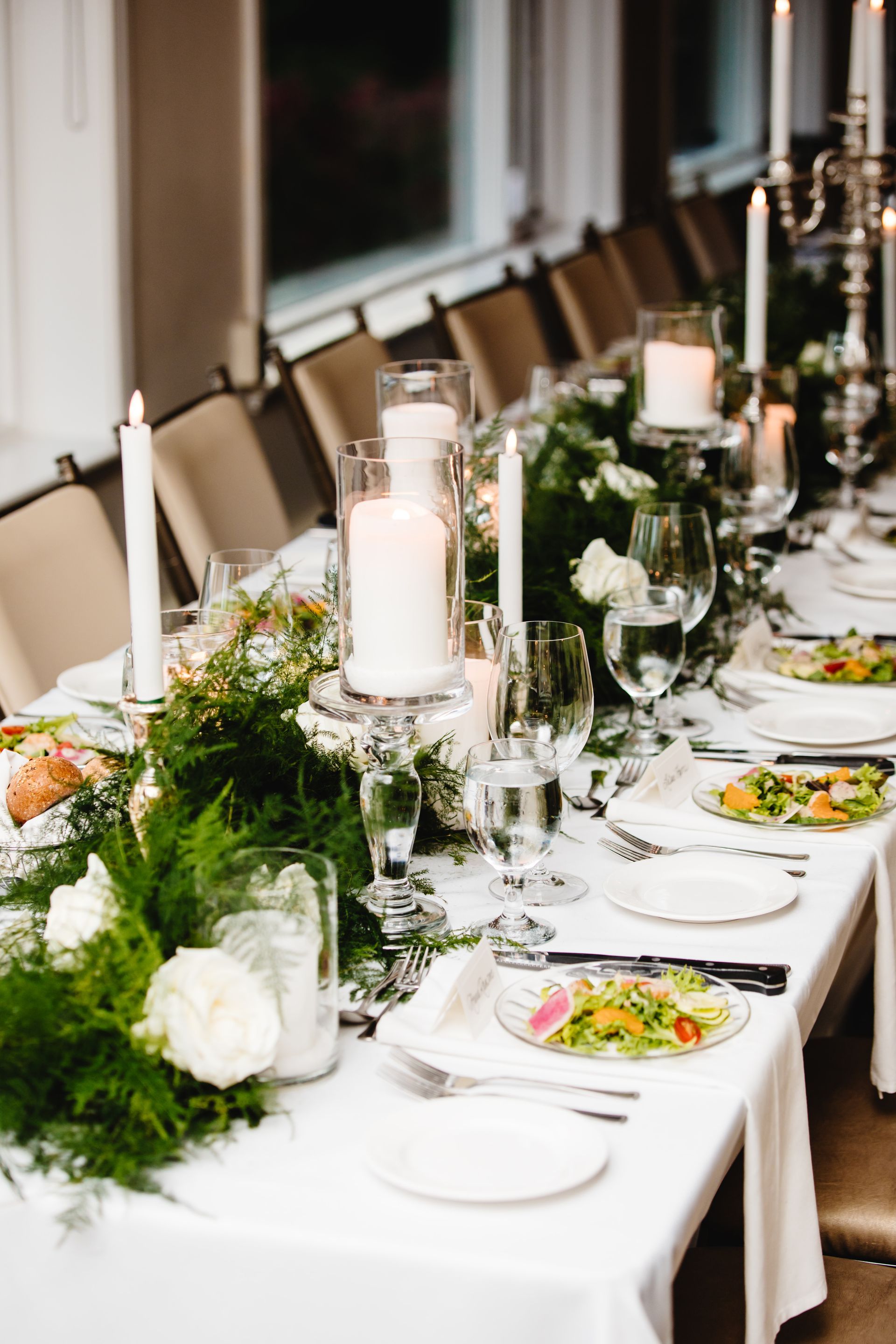 A long table with plates , candles , and flowers on it.