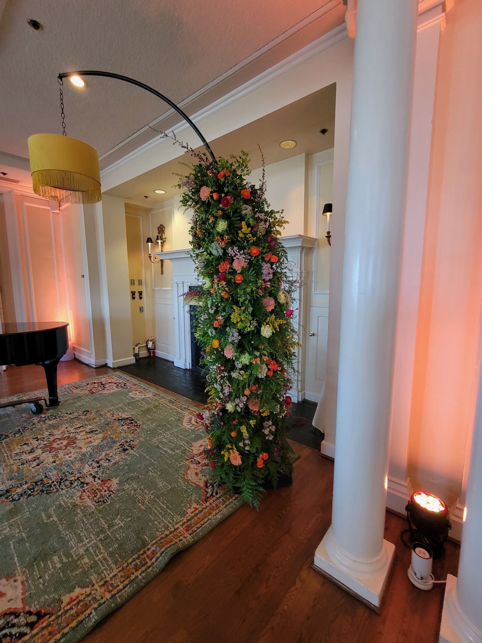 A living room with a piano , columns , and a floral arch.