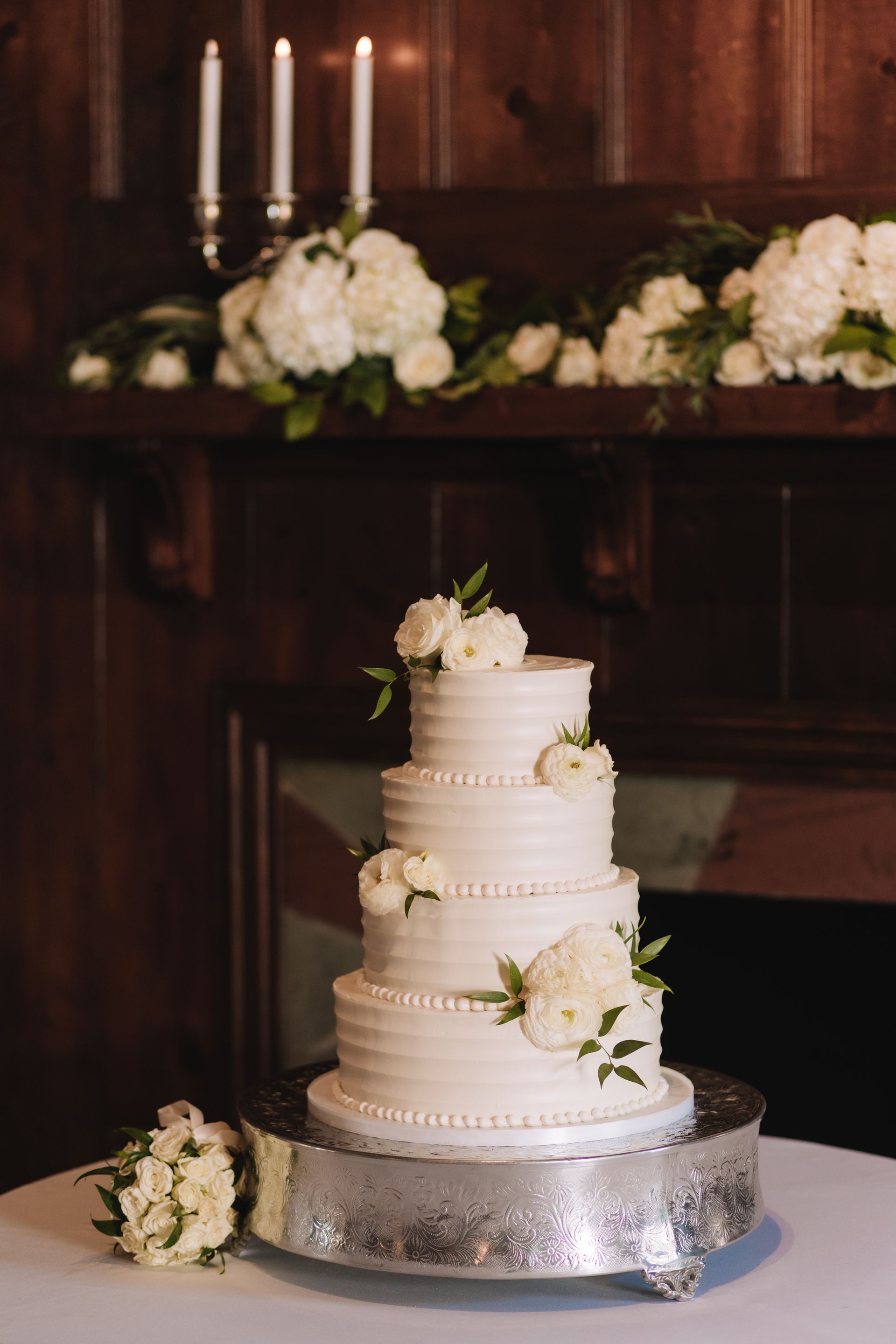 A wedding cake is sitting on top of a silver cake stand on a table.