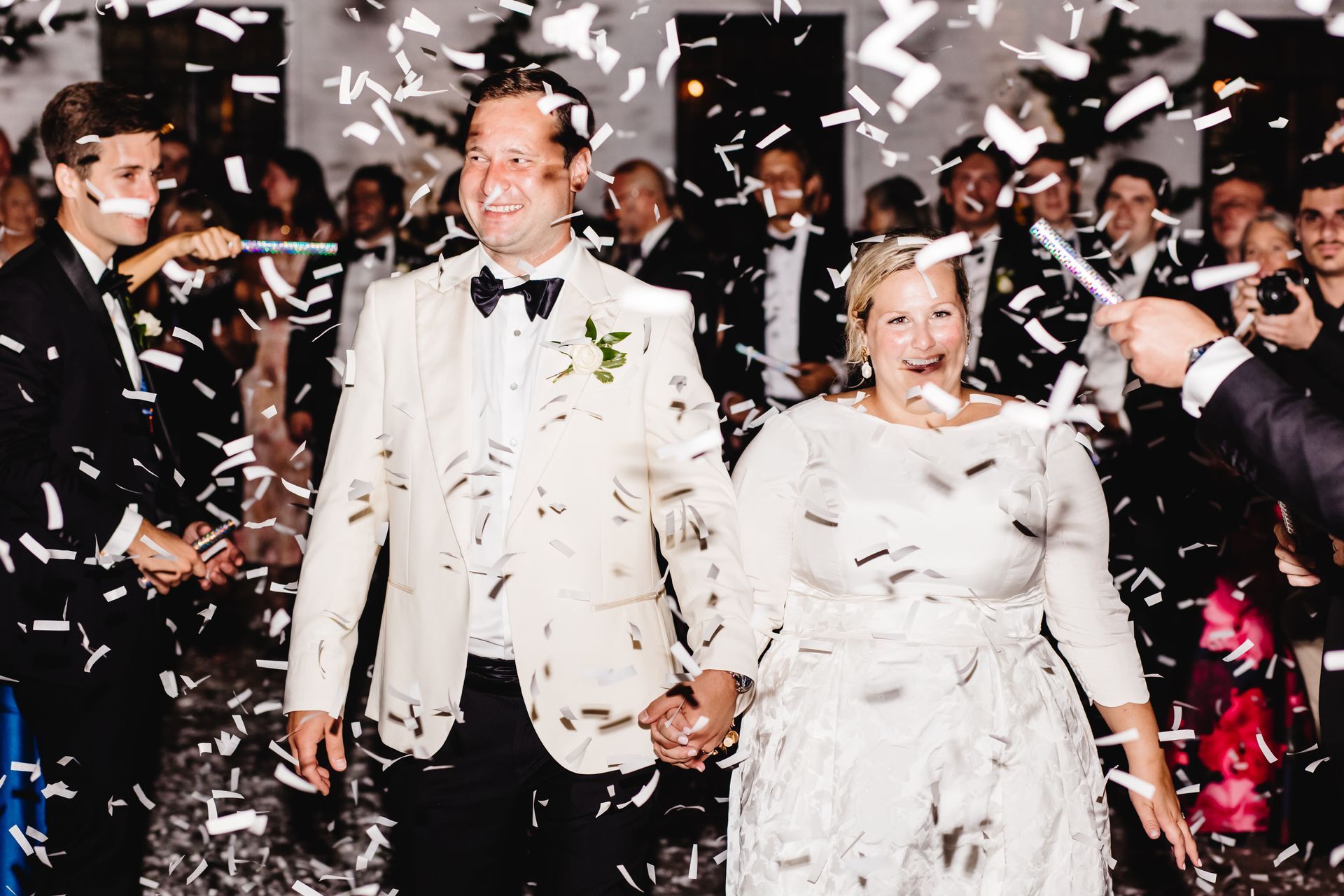 A bride and groom are walking down the aisle surrounded by confetti.