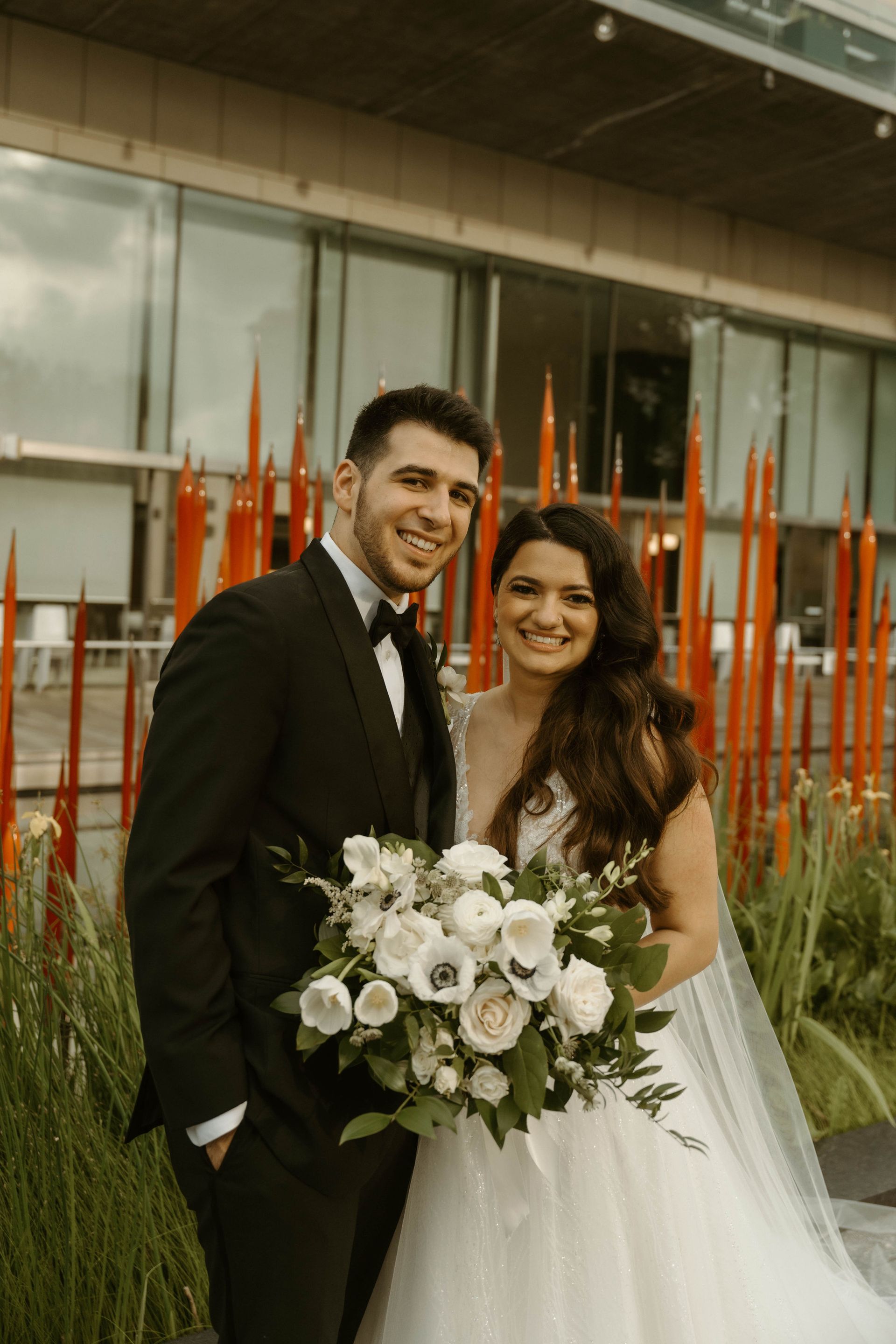 A bride and groom are posing for a picture in front of a building.