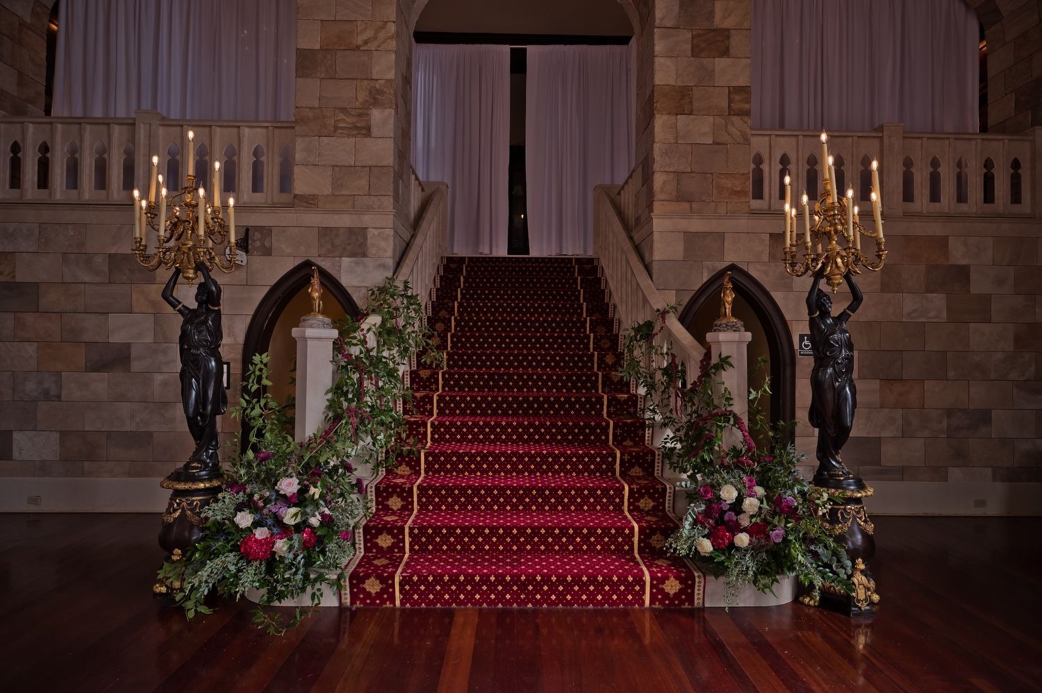 The stairs are decorated with flowers and candles and have a red carpet.