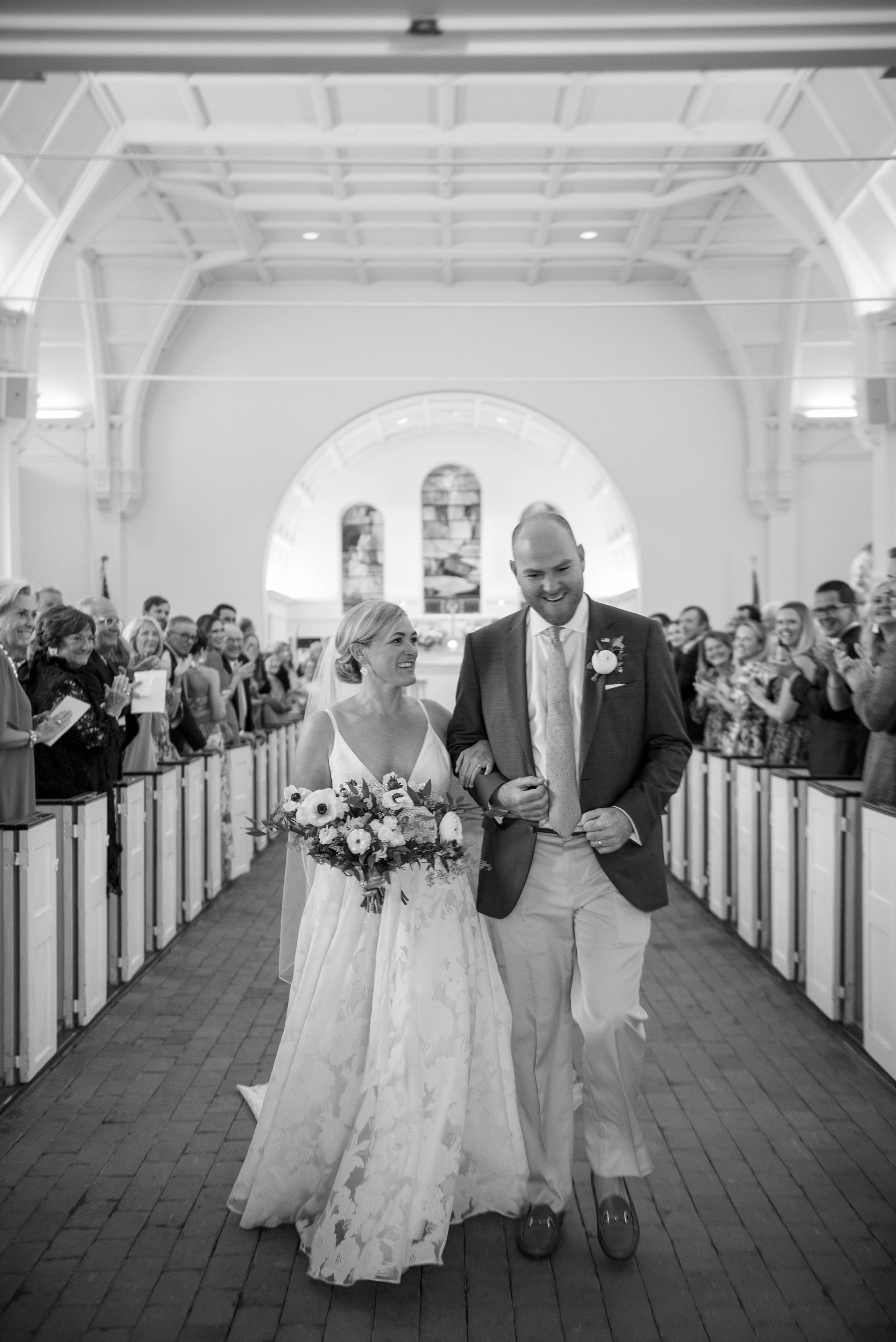 A bride and groom are walking down the aisle of a church.