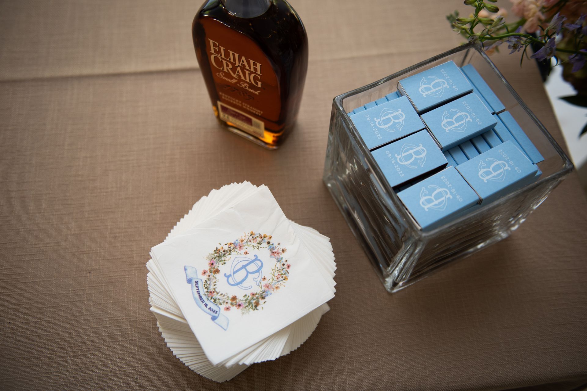 A bottle of bourbon is sitting on a table next to a stack of napkins.