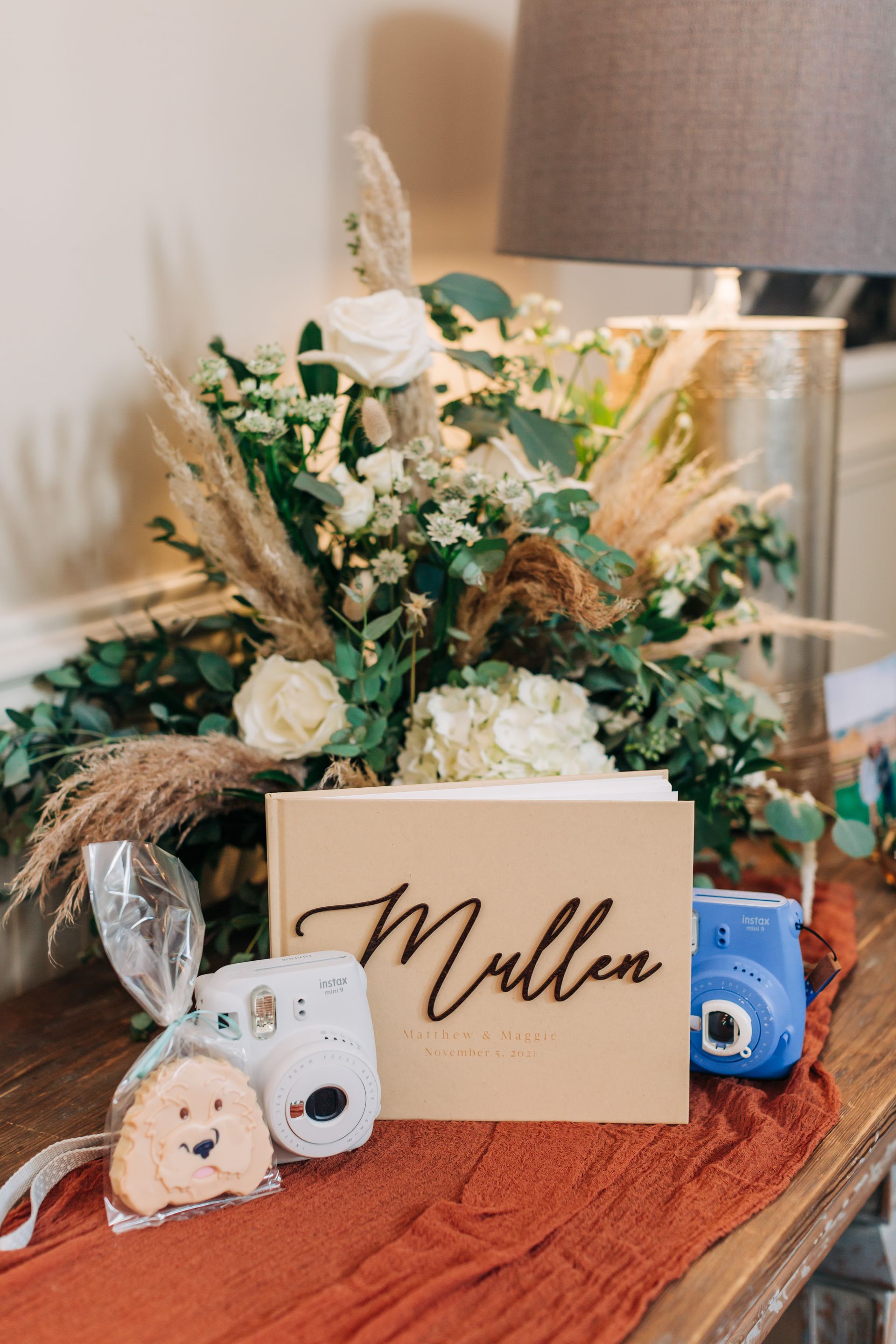 A wooden box with the name miller written on it is sitting on a table next to a vase of flowers.