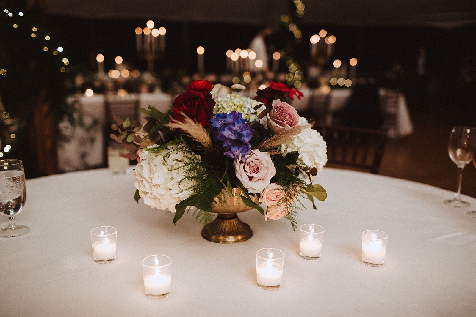 A table with a vase of flowers and candles on it.