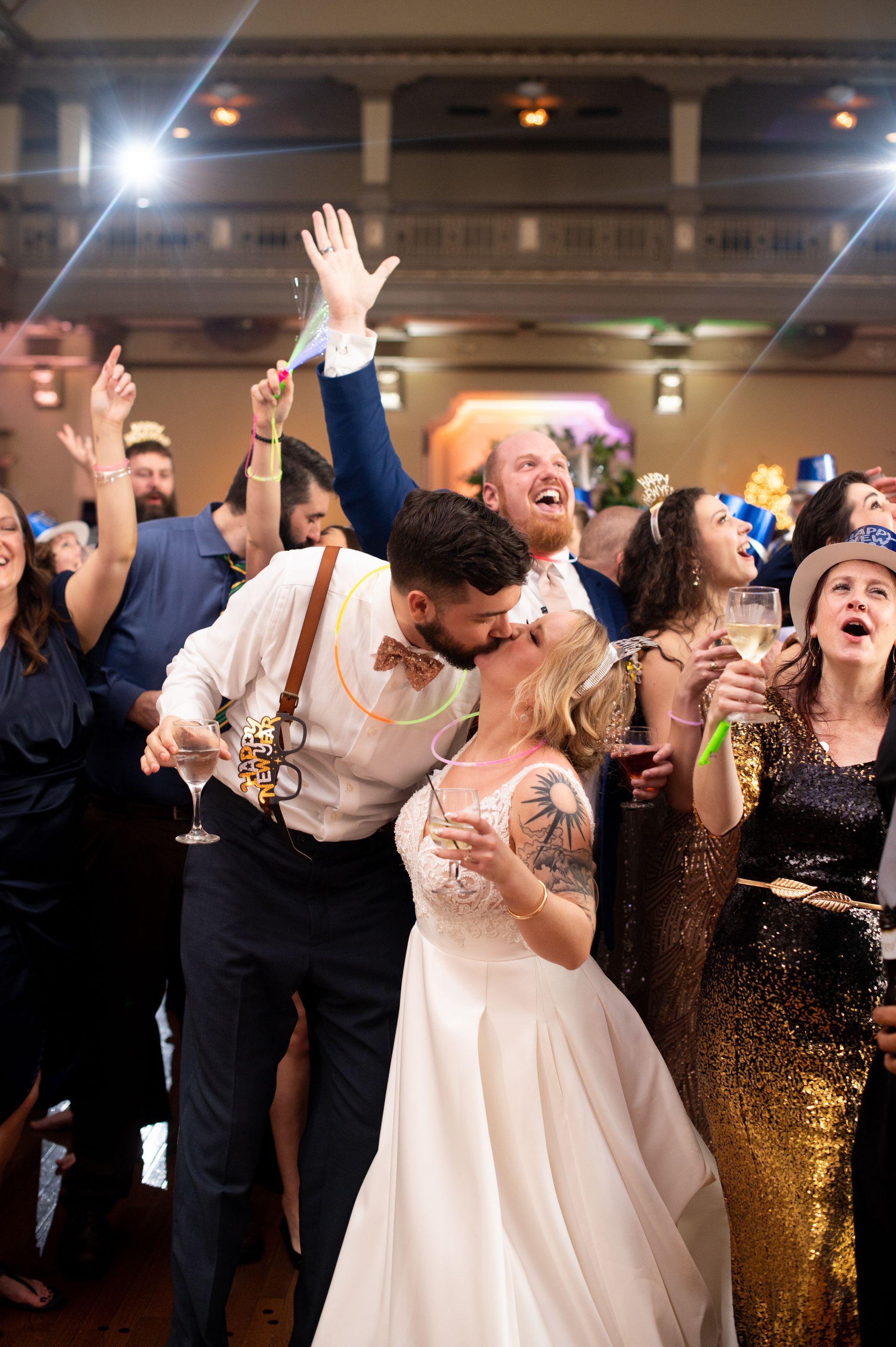 A bride and groom are kissing in front of a crowd of people at their wedding reception.