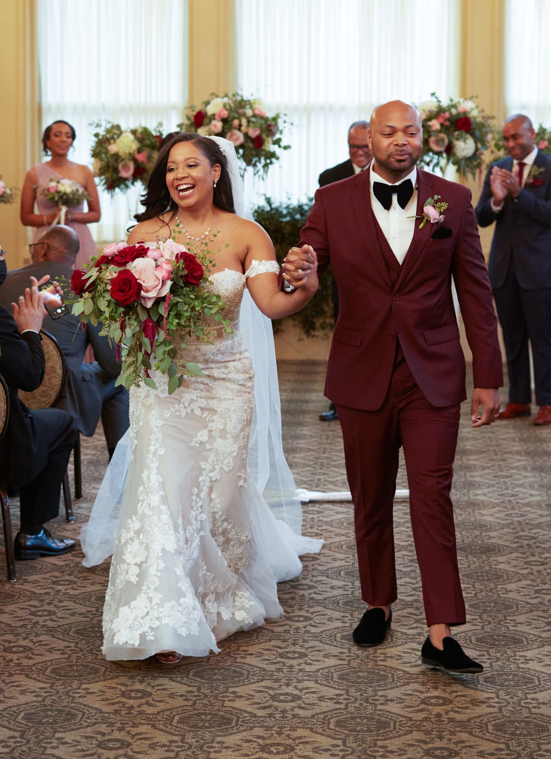 A bride and groom are walking down the aisle at their wedding holding hands.