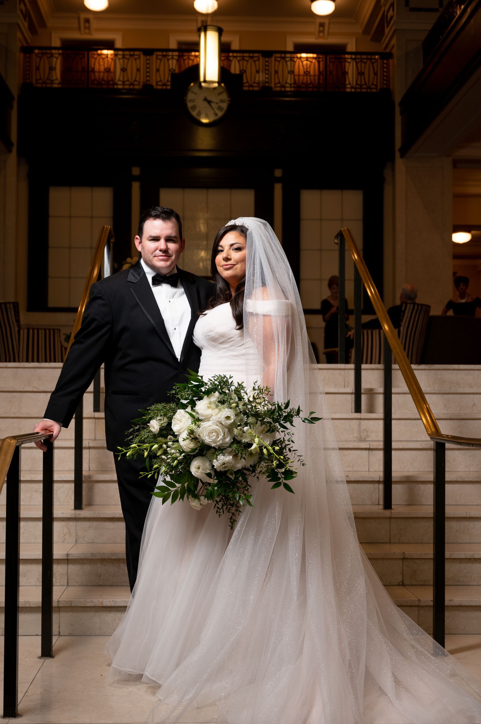 A bride and groom are posing for a picture on a set of stairs.