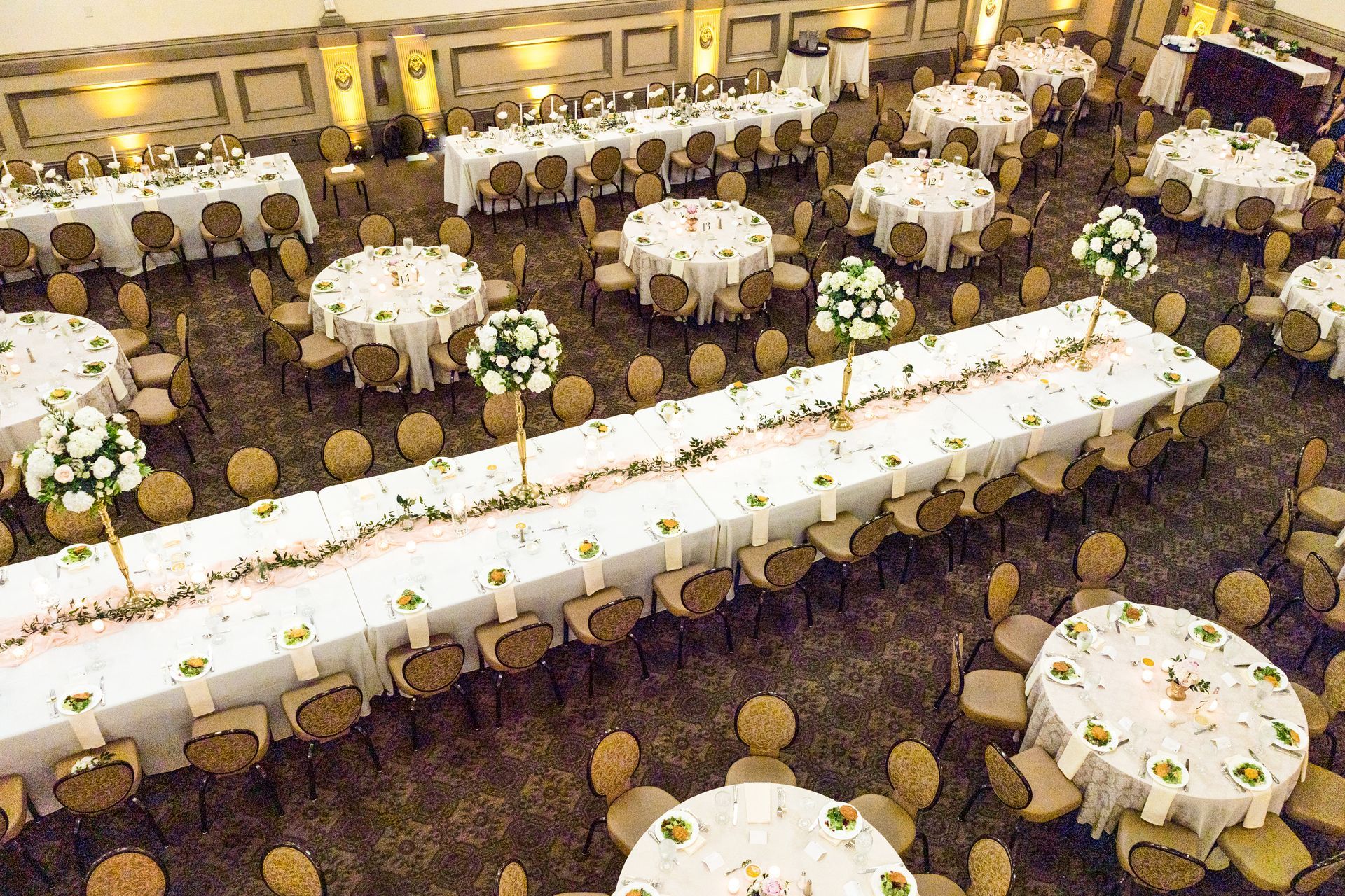 A large room filled with tables and chairs set up for a wedding reception.
