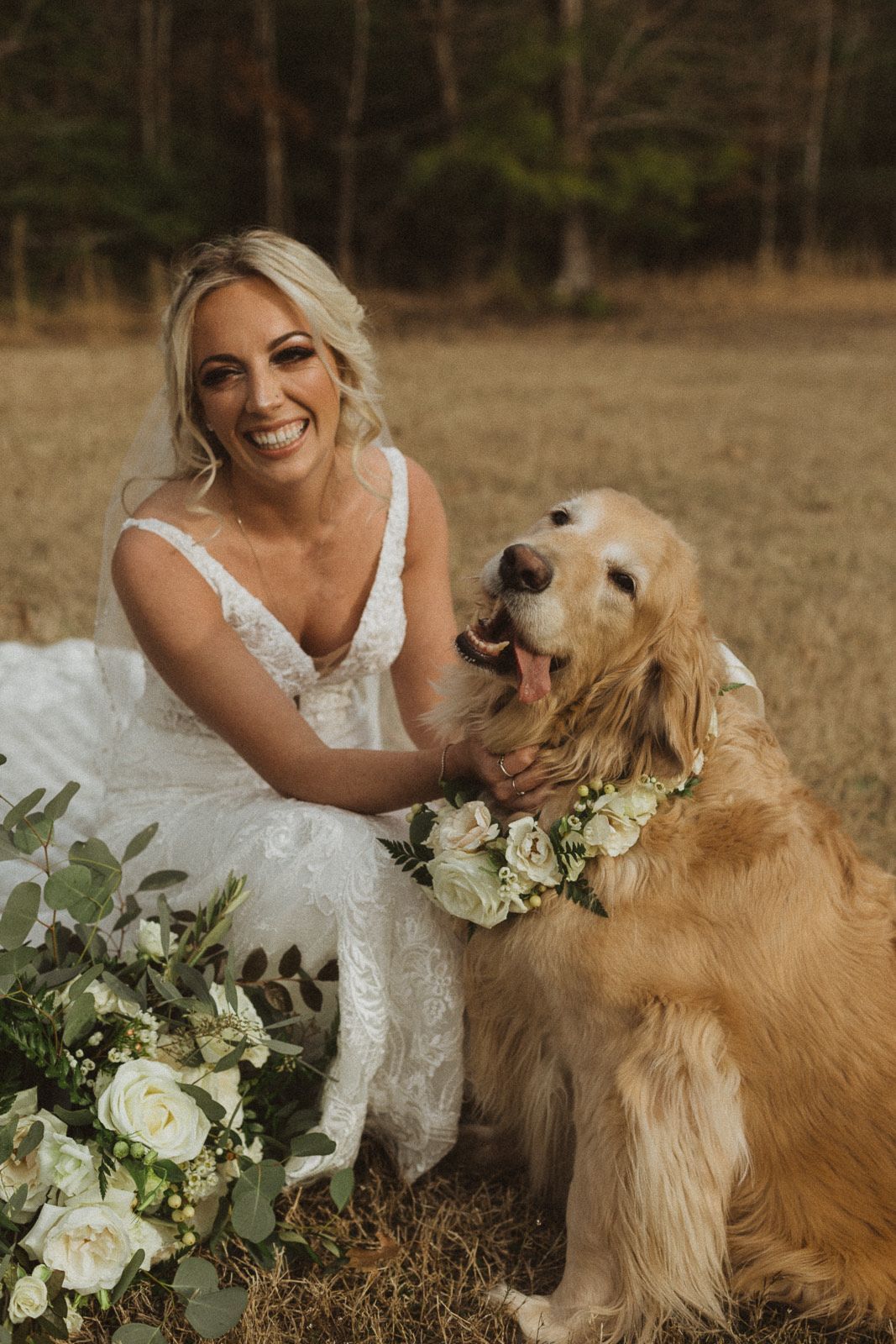 A bride is sitting next to a dog wearing a flower collar.